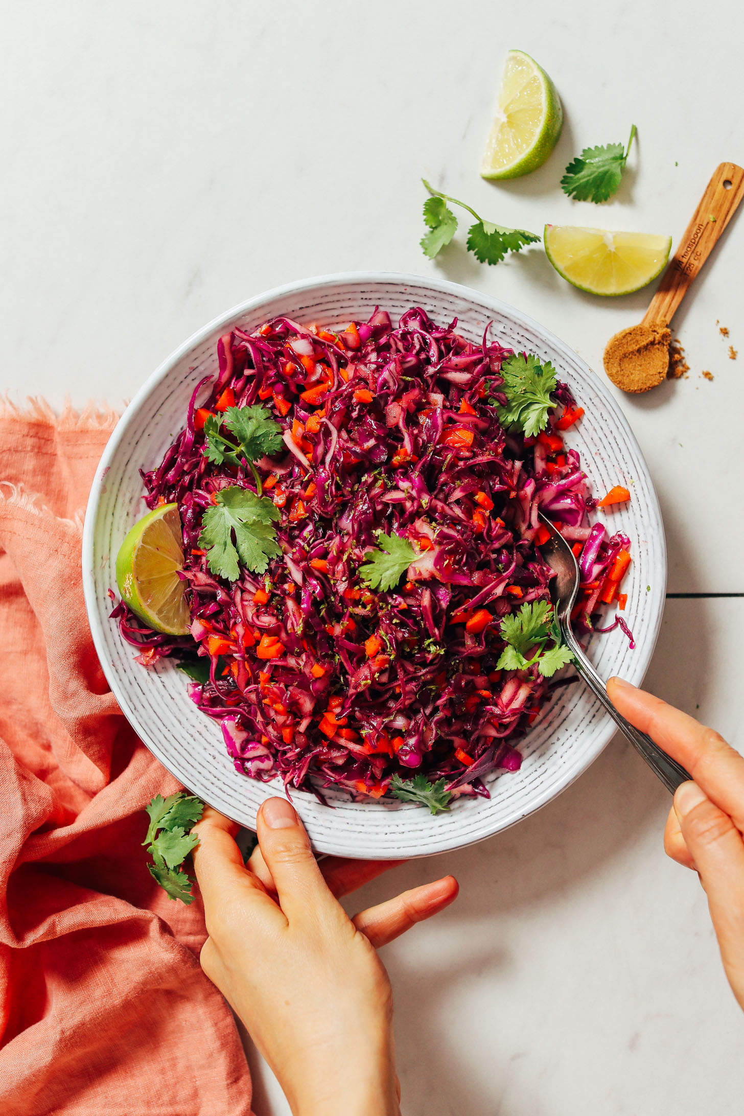 Using a spoon to stir a bowl of Quick Citrusy Cabbage Slaw
