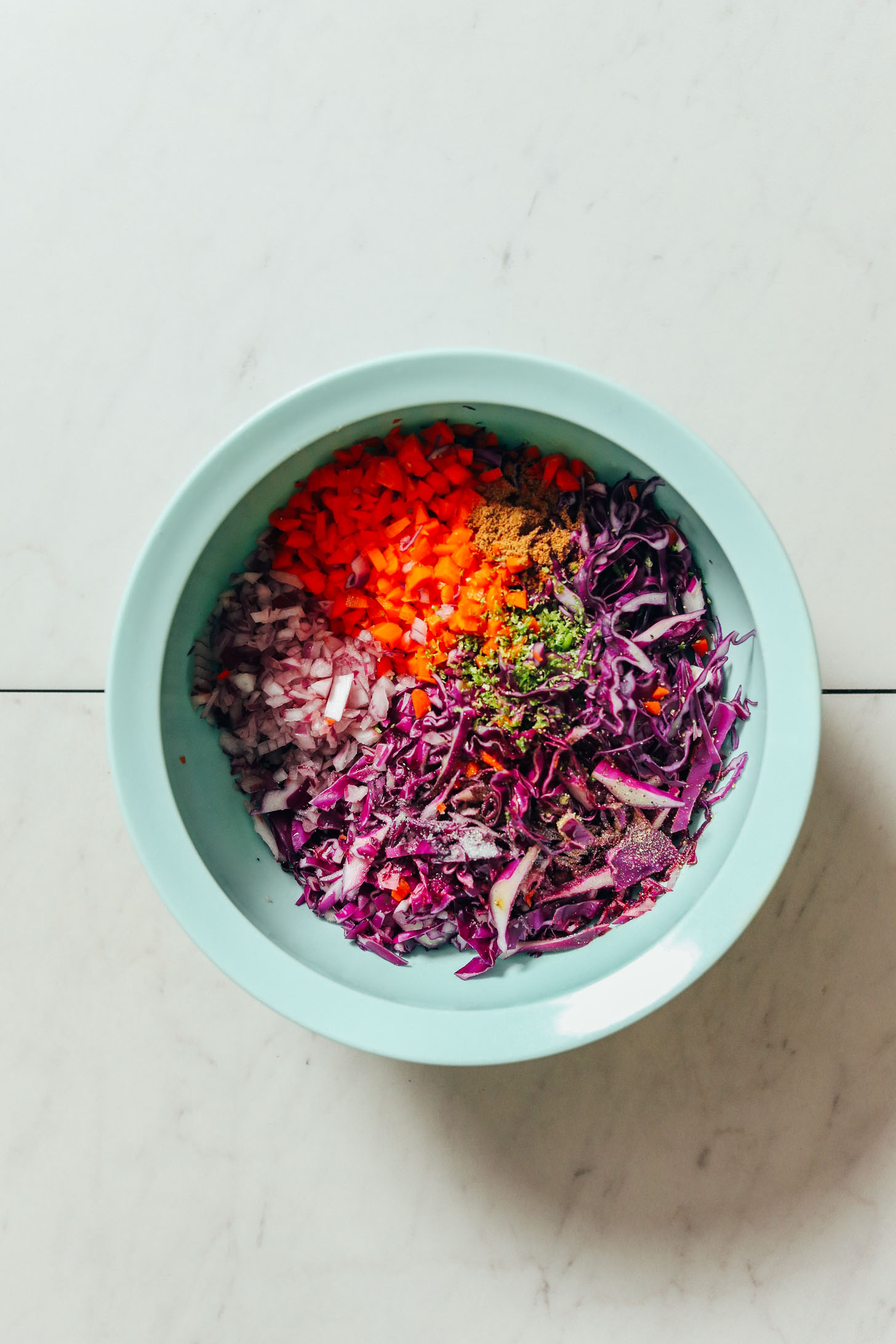 Bowl of chopped vegetables, lime zest, and spices