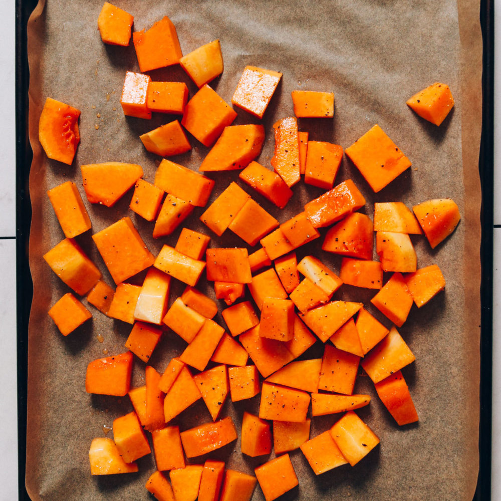 Cubed butternut squash on a parchment-lined baking sheet