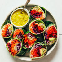 Veggie collard wraps with a bowl of Green Curry Tahini Sauce