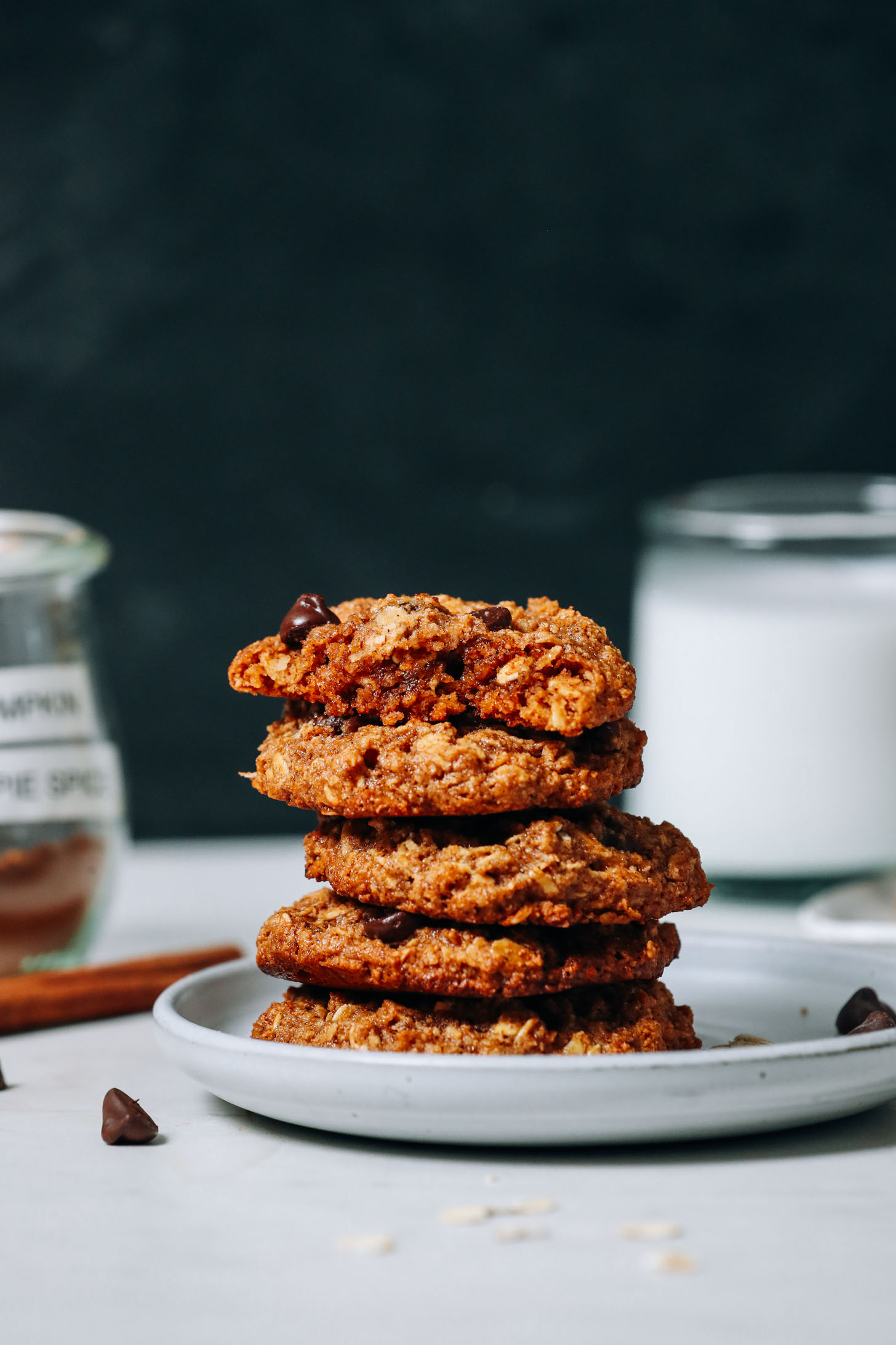 Dairy-free milk and pumpkin pie spice next to a stack of Pumpkin Chocolate Chip Cookies