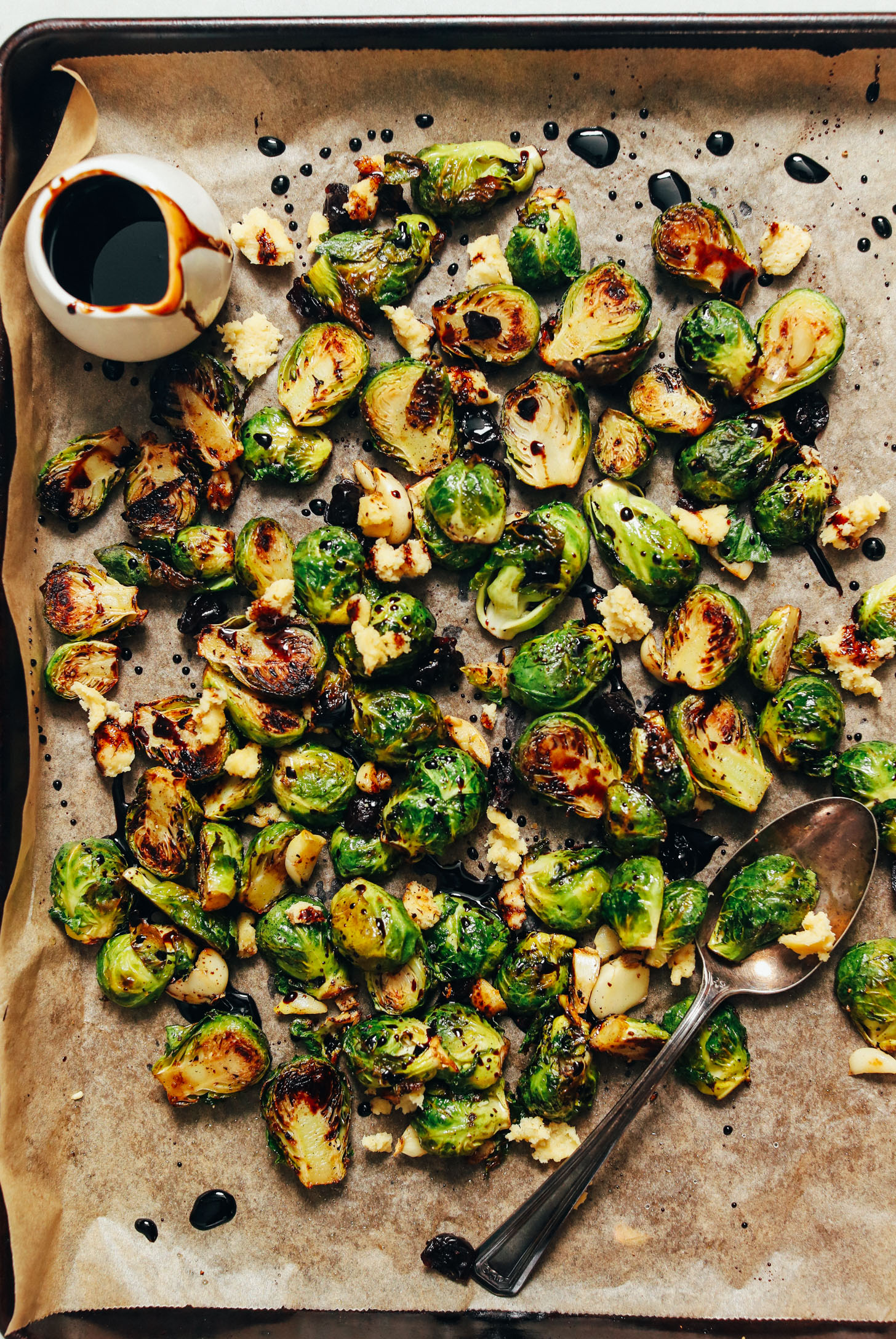 Baking sheet of roasted Brussels sprouts drizzled with balsamic reduction
