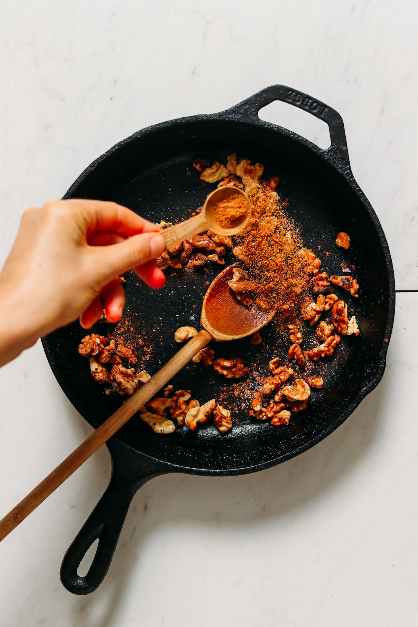 Sprinkling coconut sugar into a pan to make candied walnuts