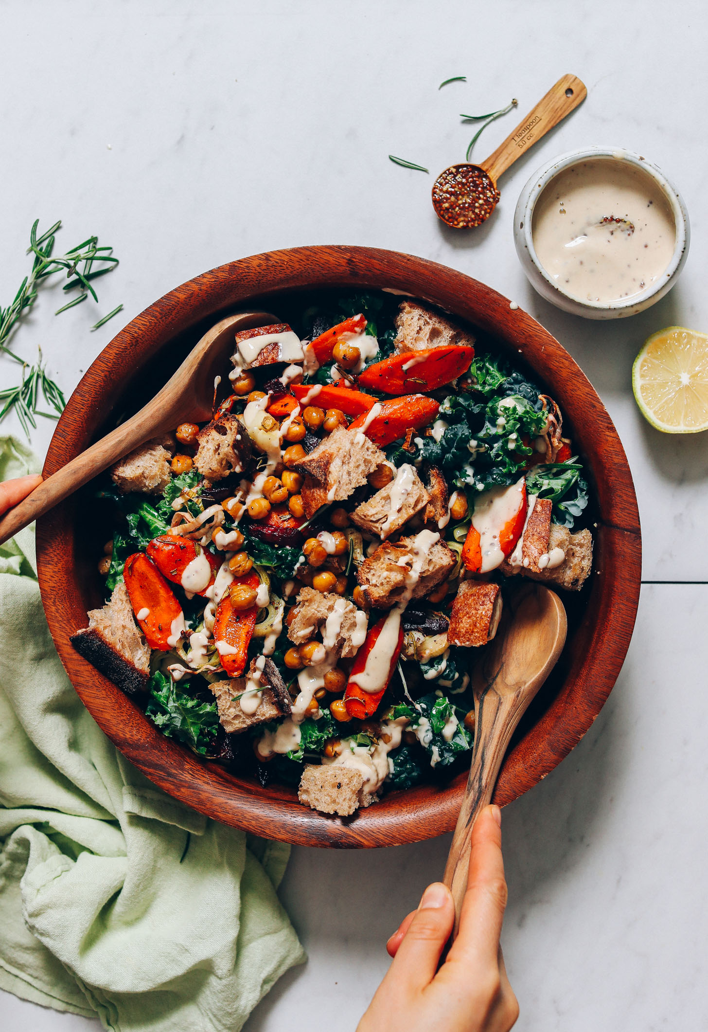 Using wood salad tongs to toss a bowl of Rosemary Roasted Root Vegetable Panzanella