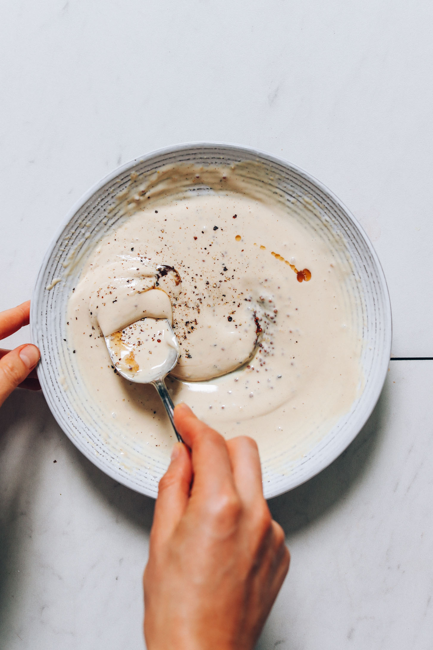 Stirring a bowl of creamy tahini mustard dressing