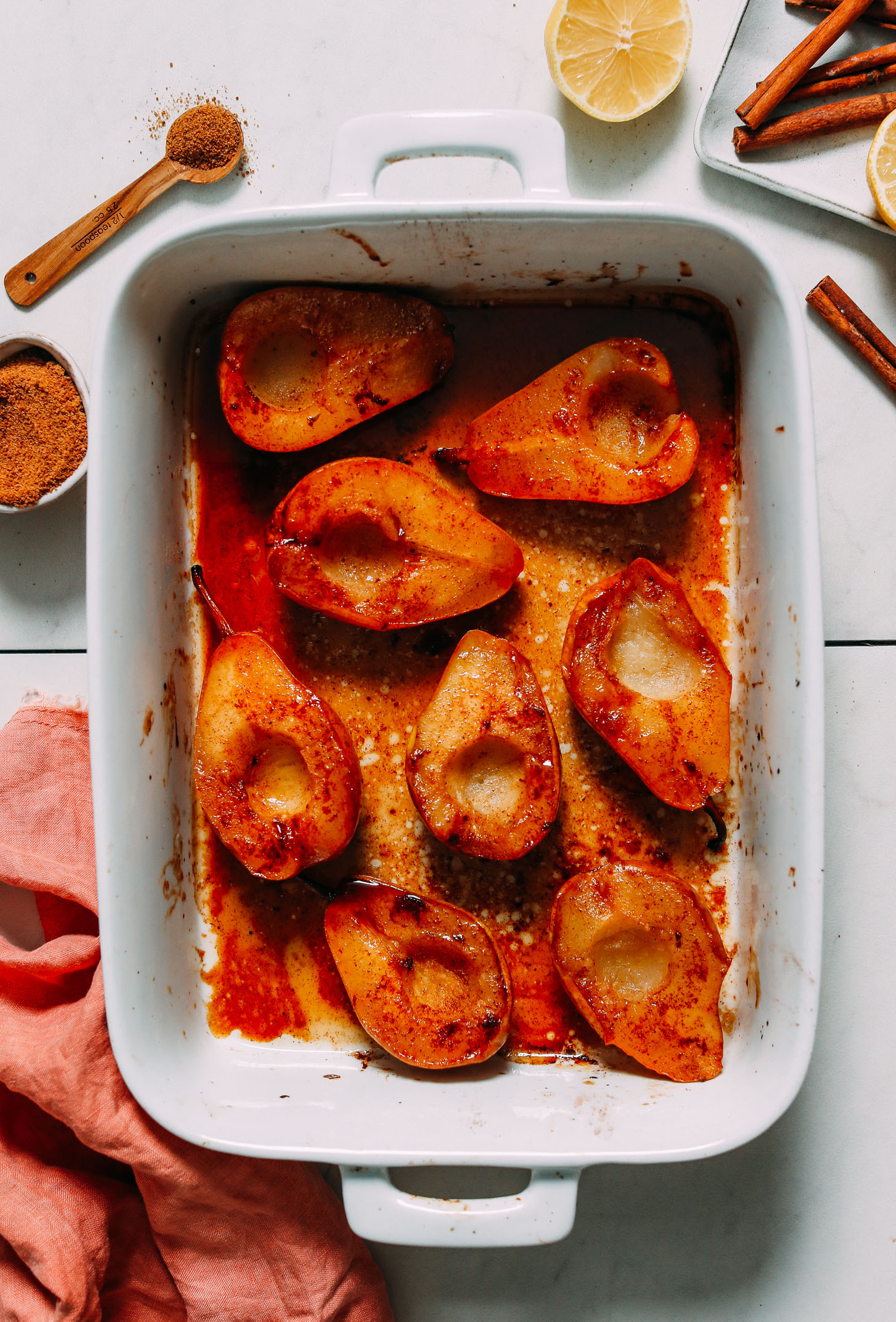 Coconut sugar, lemons, and cinnamon next to a pan of easy baked pears