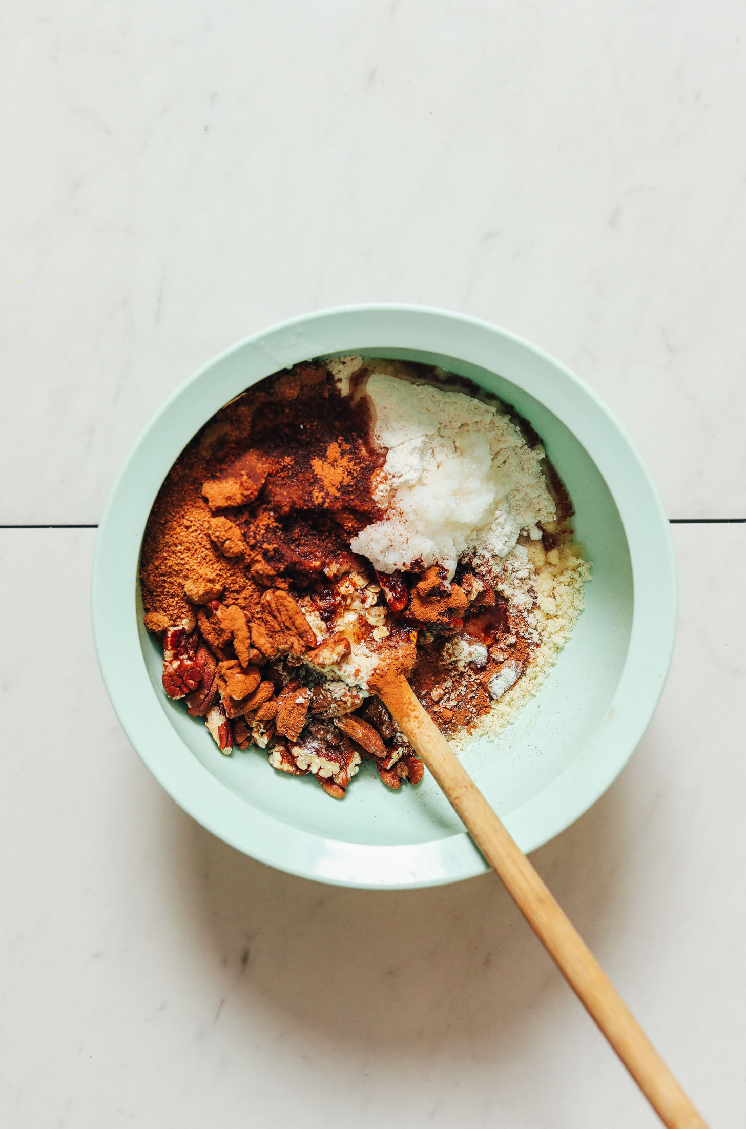 Bowl of gluten-free oats, almond flour, pecans, coconut sugar, cinnamon, sea salt, and maple syrup