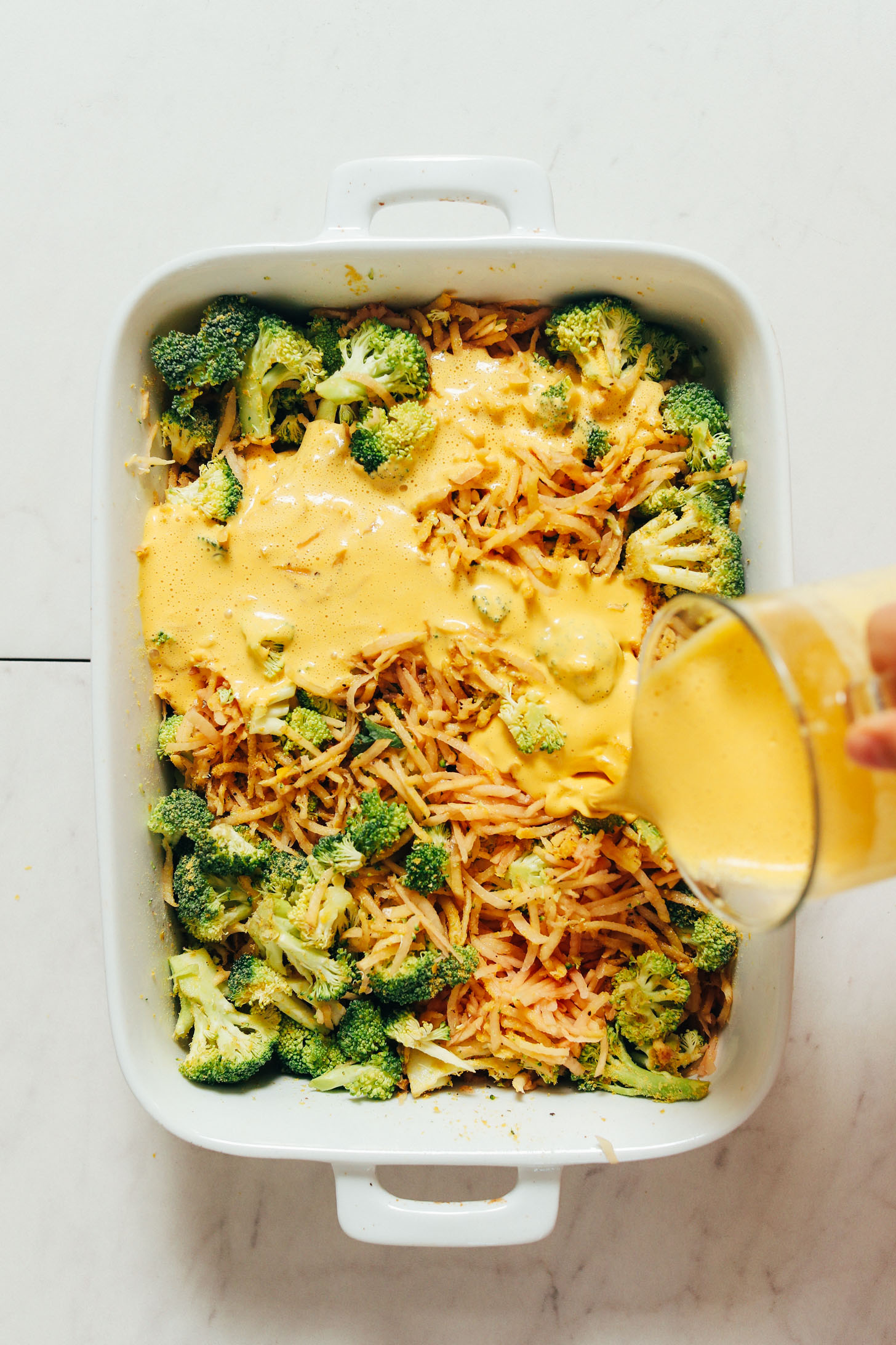 Pouring vegan cashew carrot sauce in a pan