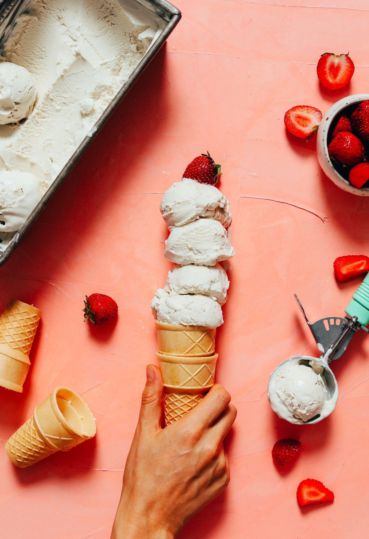 Holding cones filled with vegan vanilla ice cream