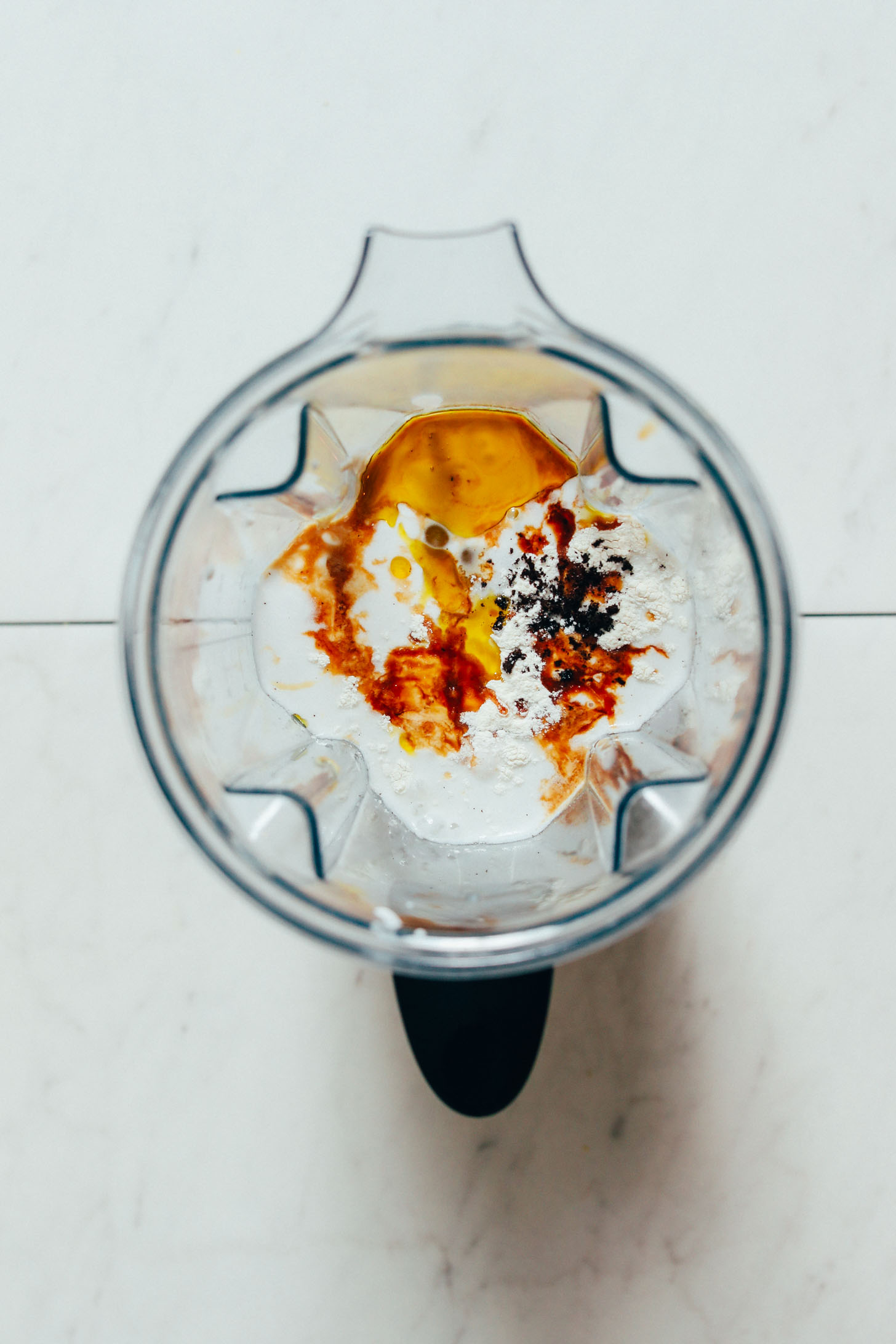 Blender filled with coconut milk, cashew butter, maple syrup, sugar, vanilla, and xanthan gum