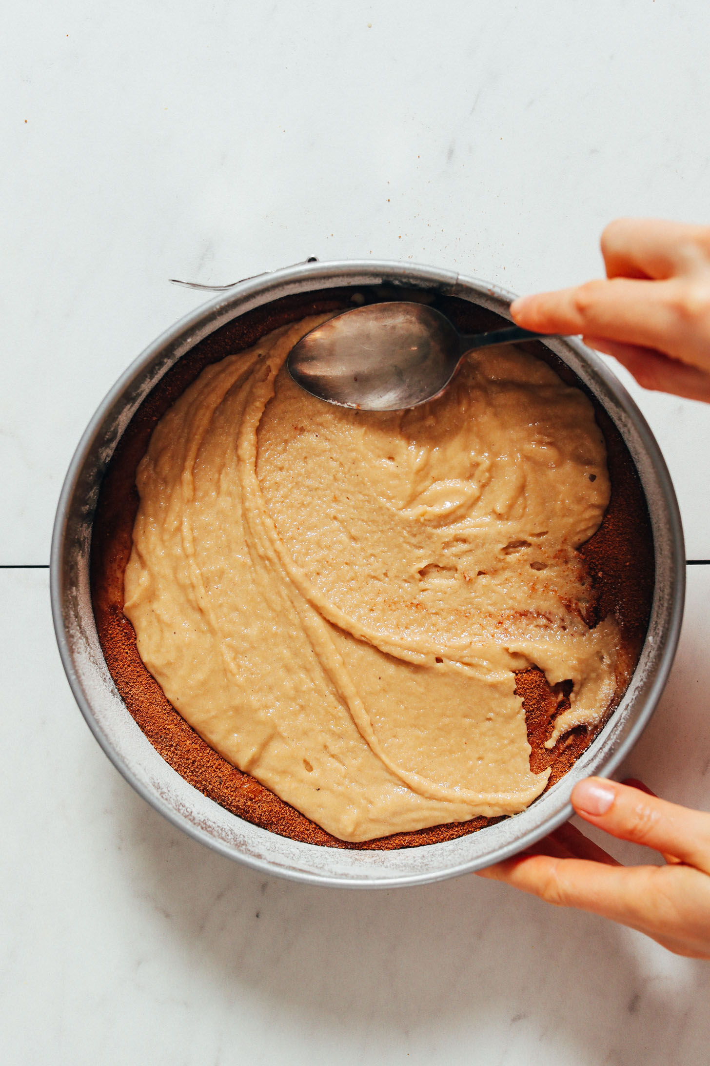 Spreading coffee cake batter over a cinnamon swirl layer