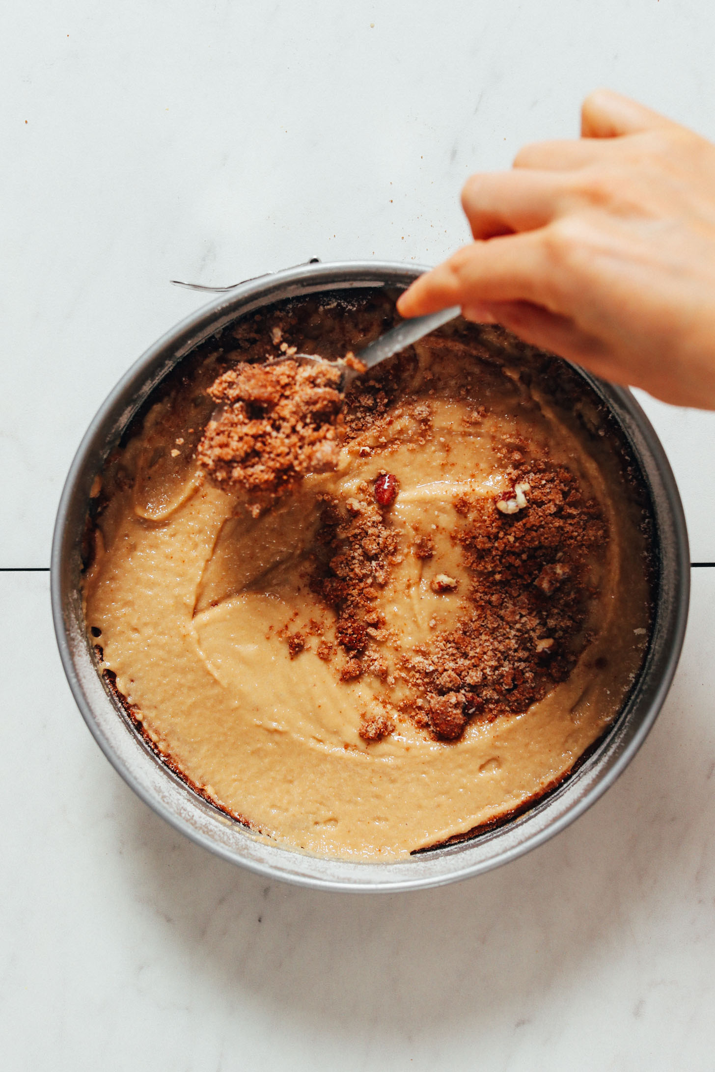 Sprinkling coconut sugar crumb topping over vegan coffee cake