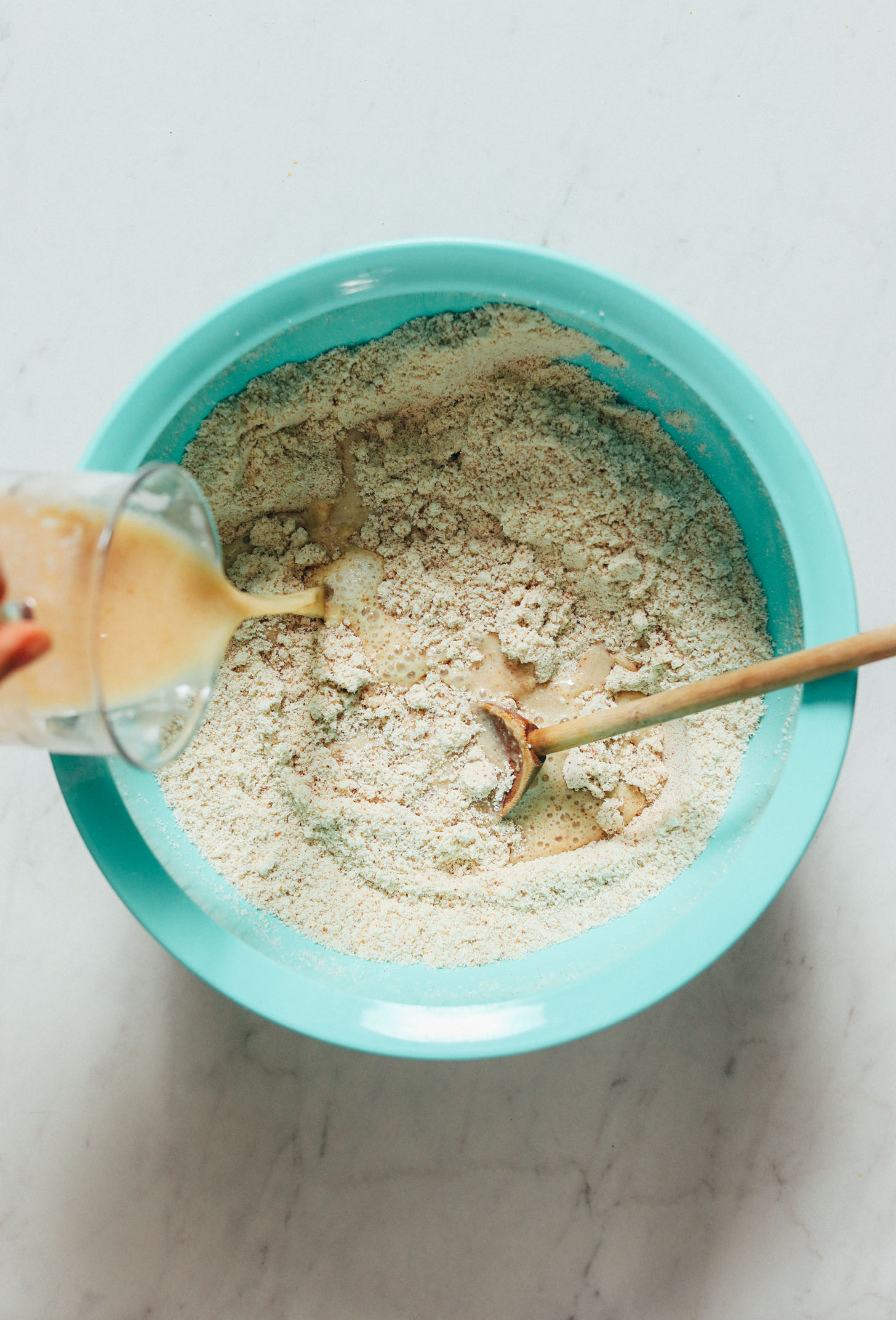 Pouring wet ingredients into dry in a mixing bowl