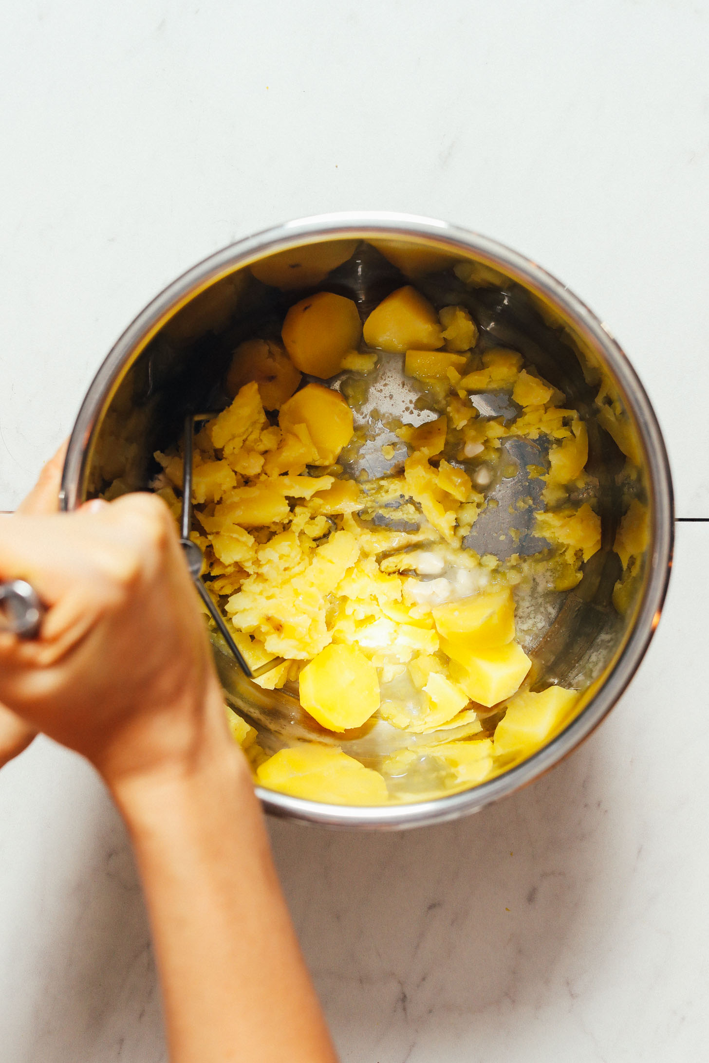 Using a potato masher to mash potatoes cooked in the Instant Pot