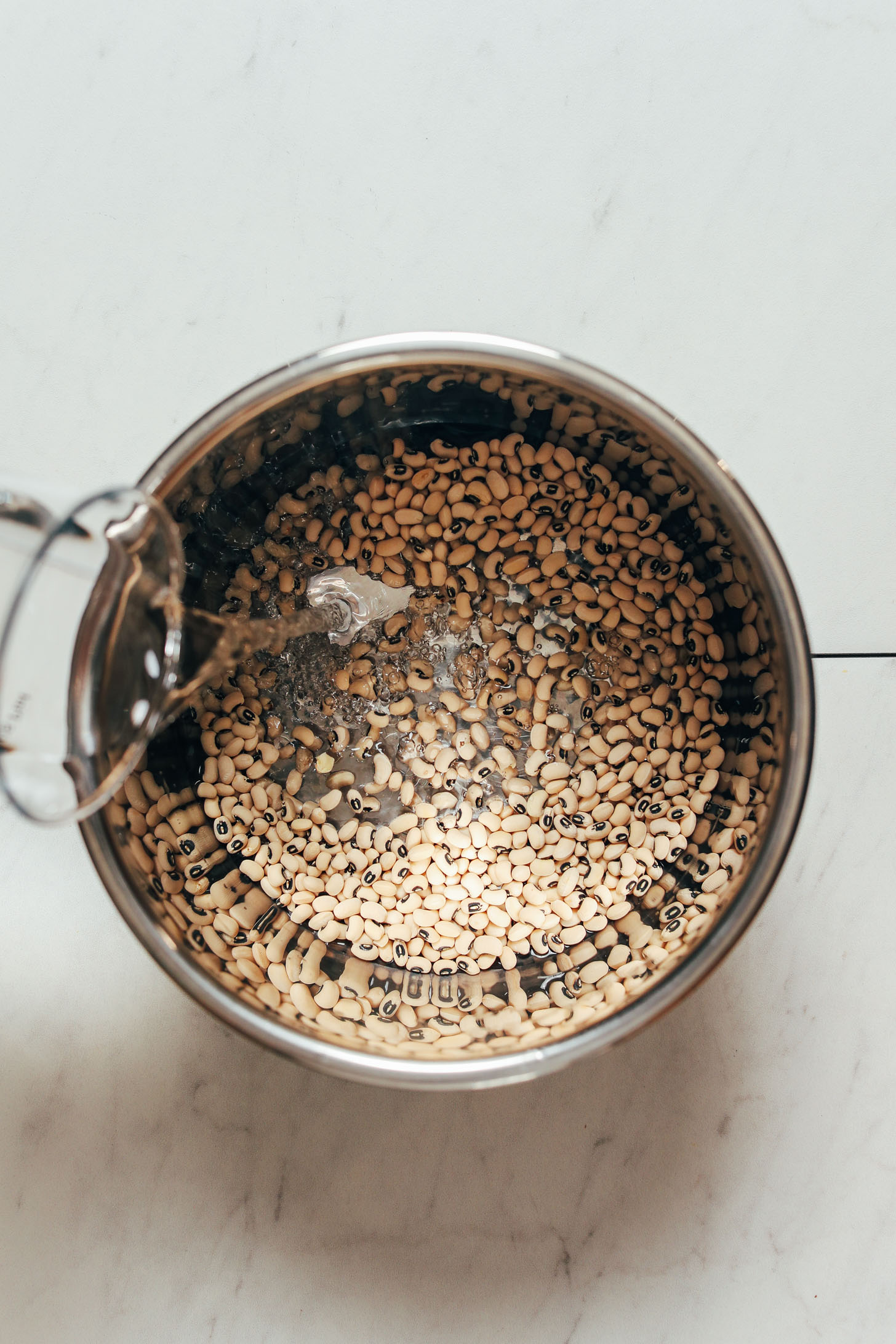 Pouring water into an Instant Pot of black eyed peas