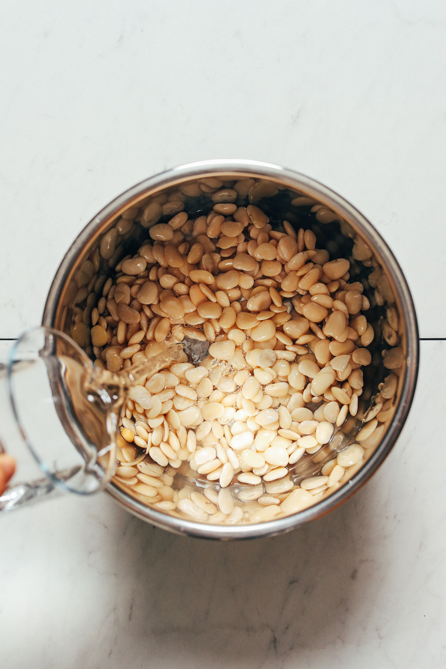 Pouring water into a pot of soaked baby lima beans