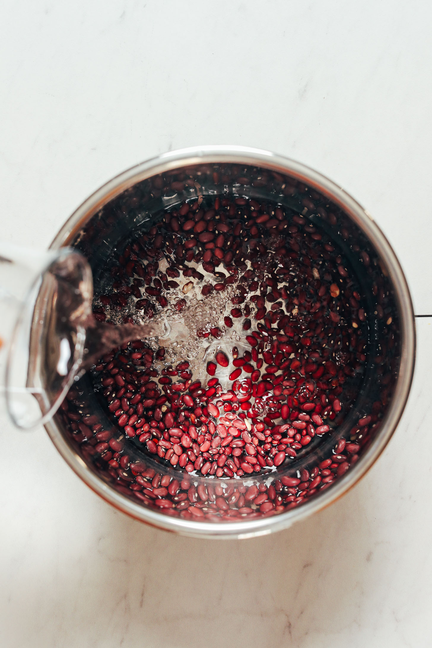 Pouring water into an Instant Pot of dry red beans