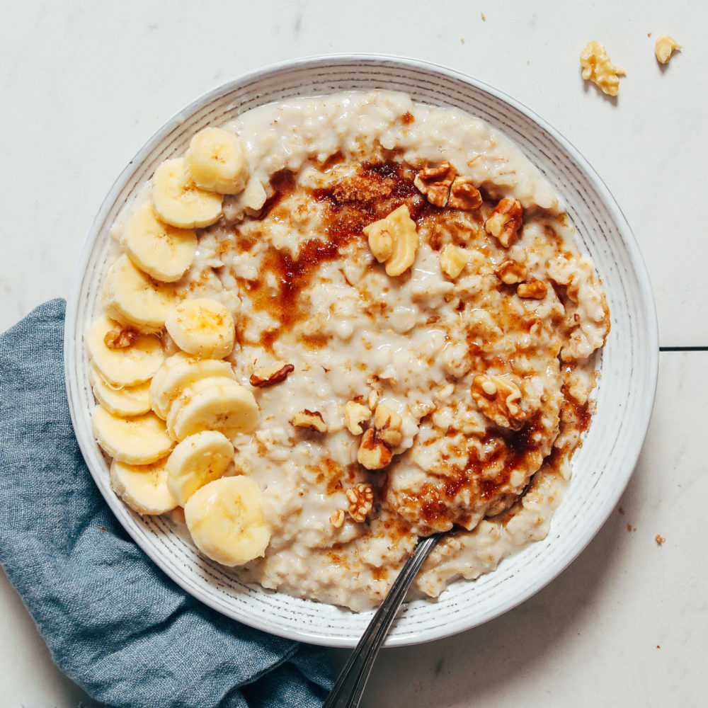 Bowl of Instant Pot oats topped with sliced banana, brown sugar, and pecans