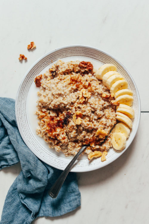 Bowl of steel cut oats with sliced banana, walnuts, and brown sugar
