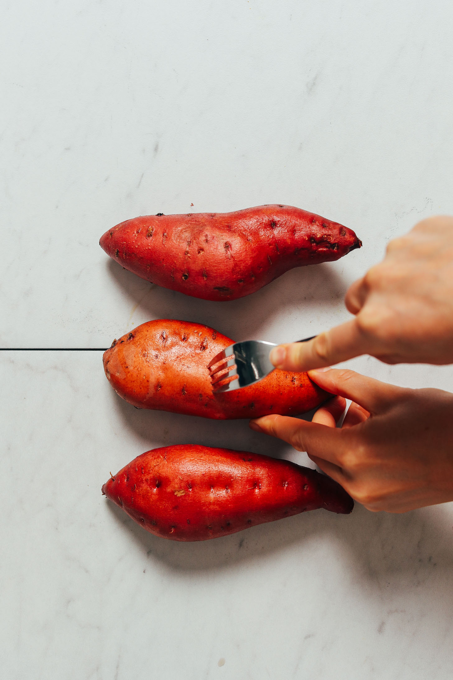 Using a fork to poke holes in sweet potatoes