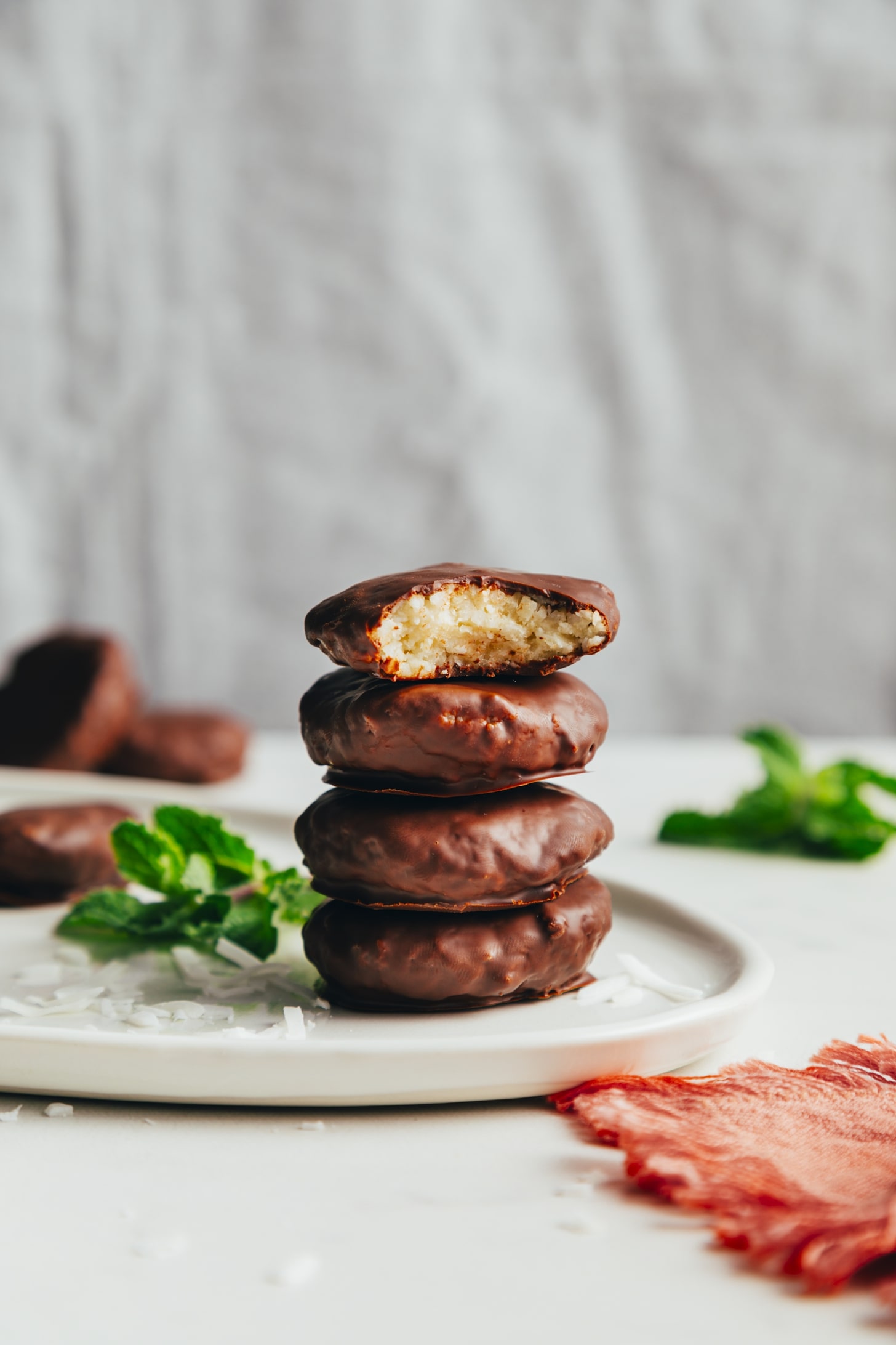 Stack of vegan peppermint patties beside fresh mint and shredded coconut
