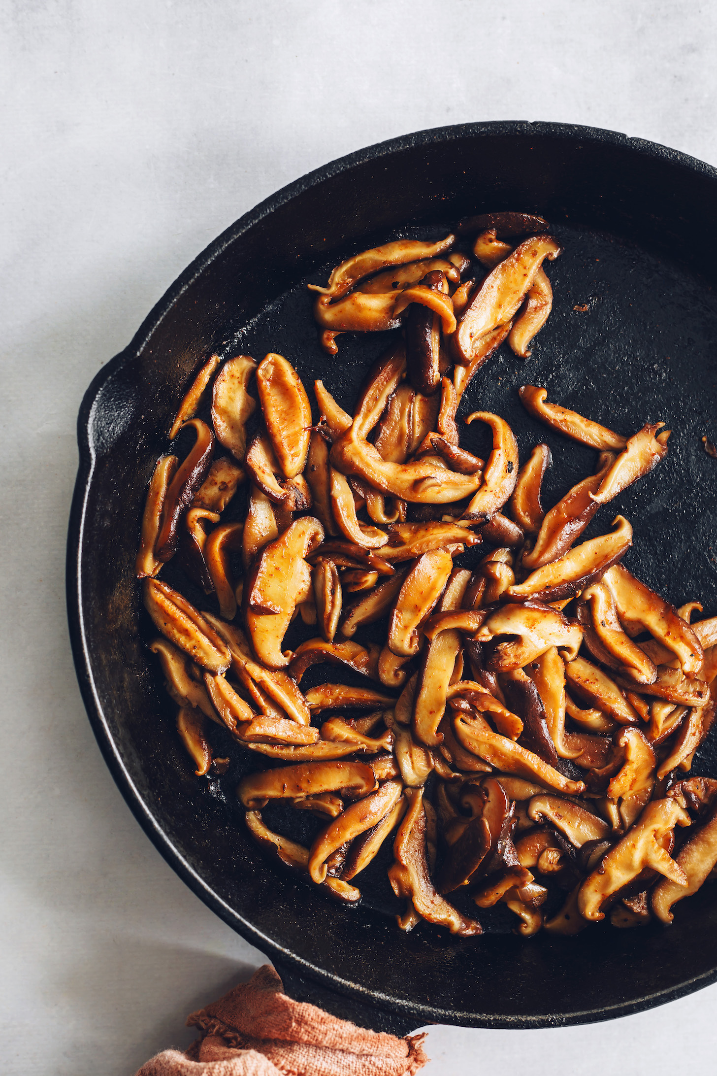 Sliced shiitake mushrooms in a cast iron skillet coated in seasonings