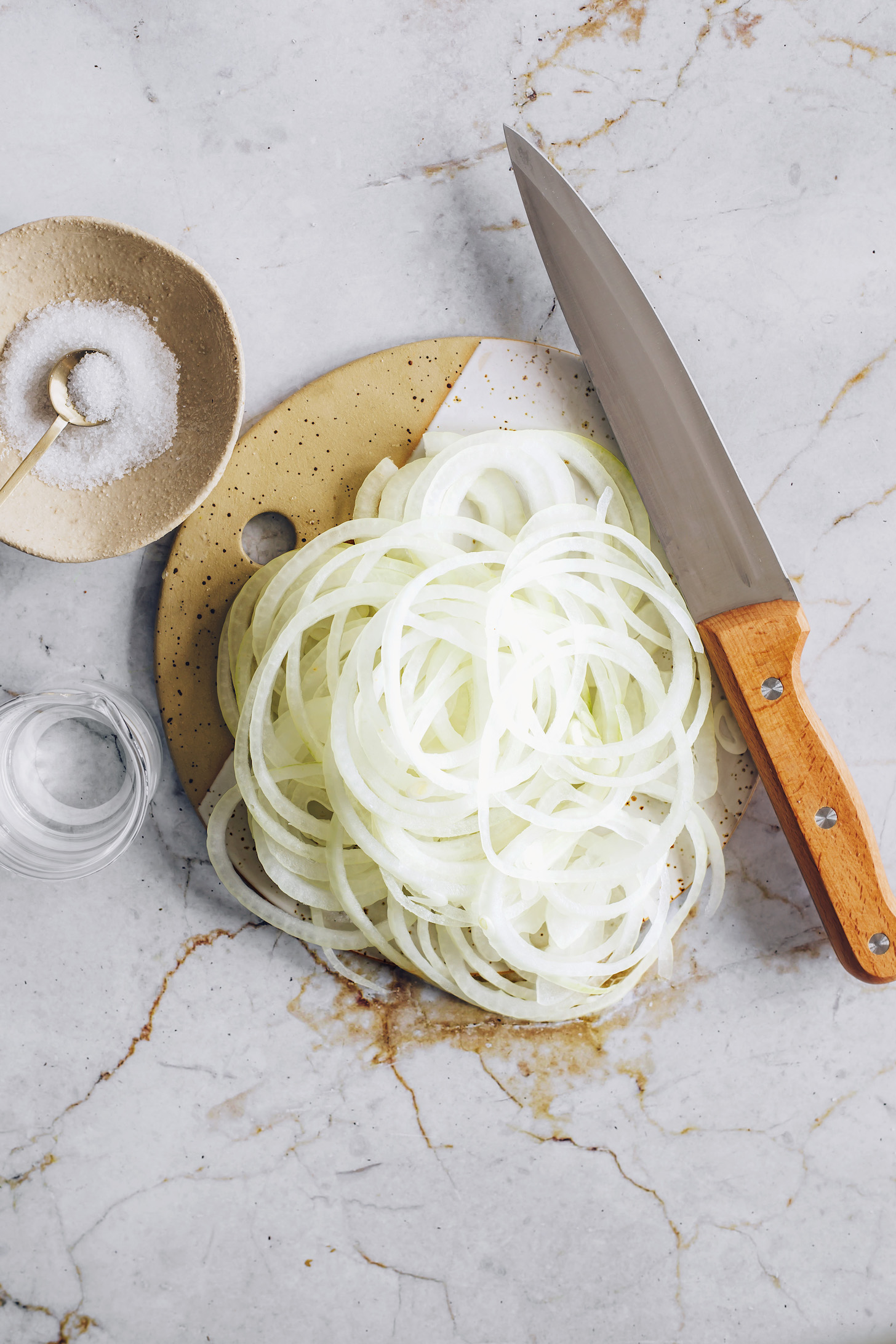 Thinly sliced onions next to a small bowl of salt