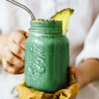 Holding a glass jar filled with our green lemonade smoothie recipe
