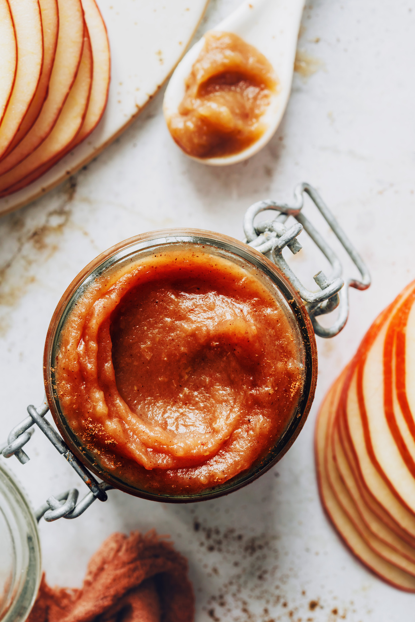 Jar of apple butter next to sliced apples