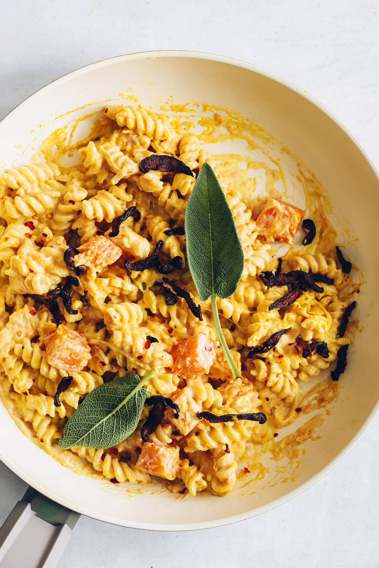 Skillet of vegan butternut squash pasta topped with sage leaves