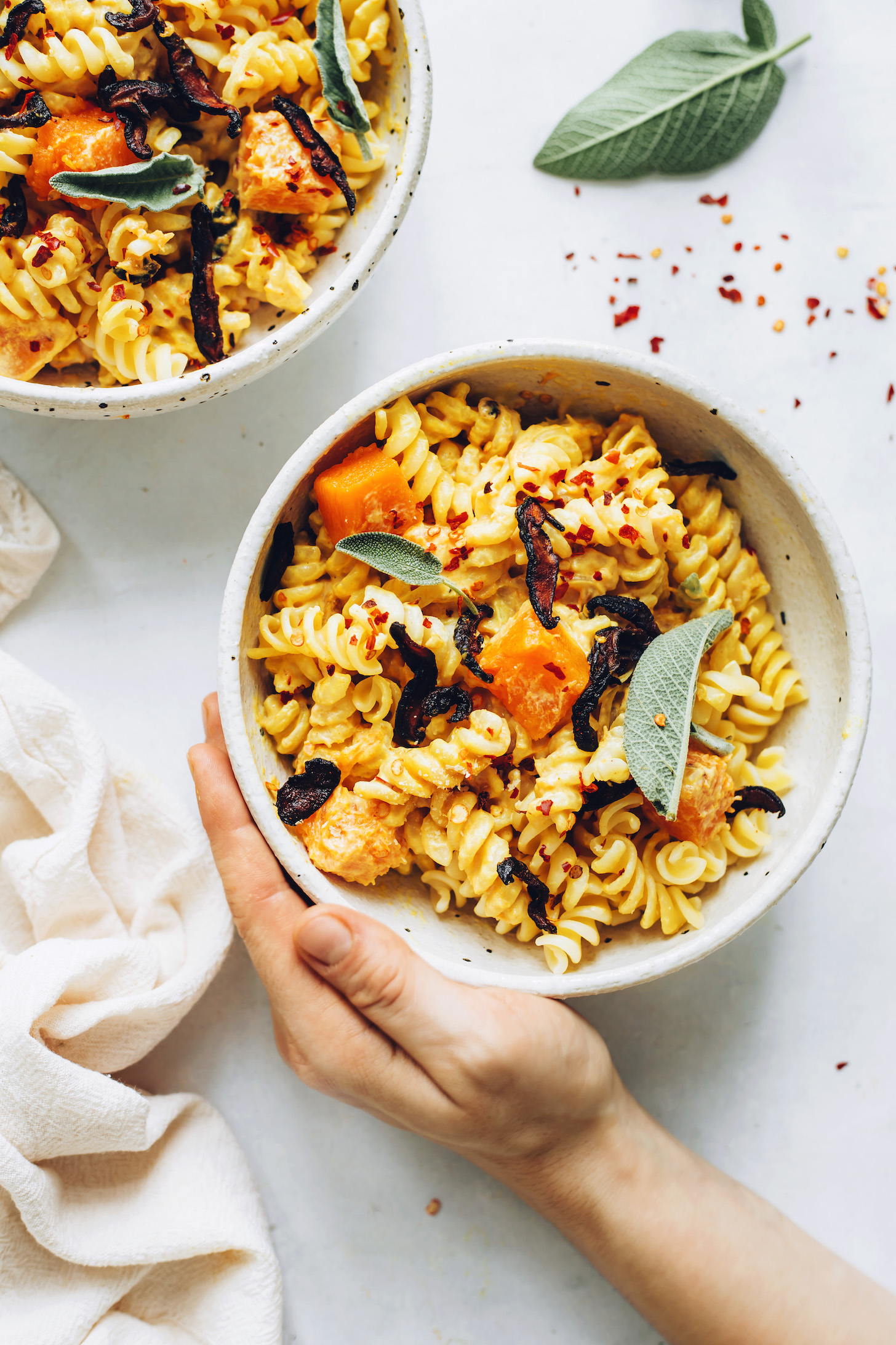 Bowls of butternut squash pasta topped with shiitake bacon and sage