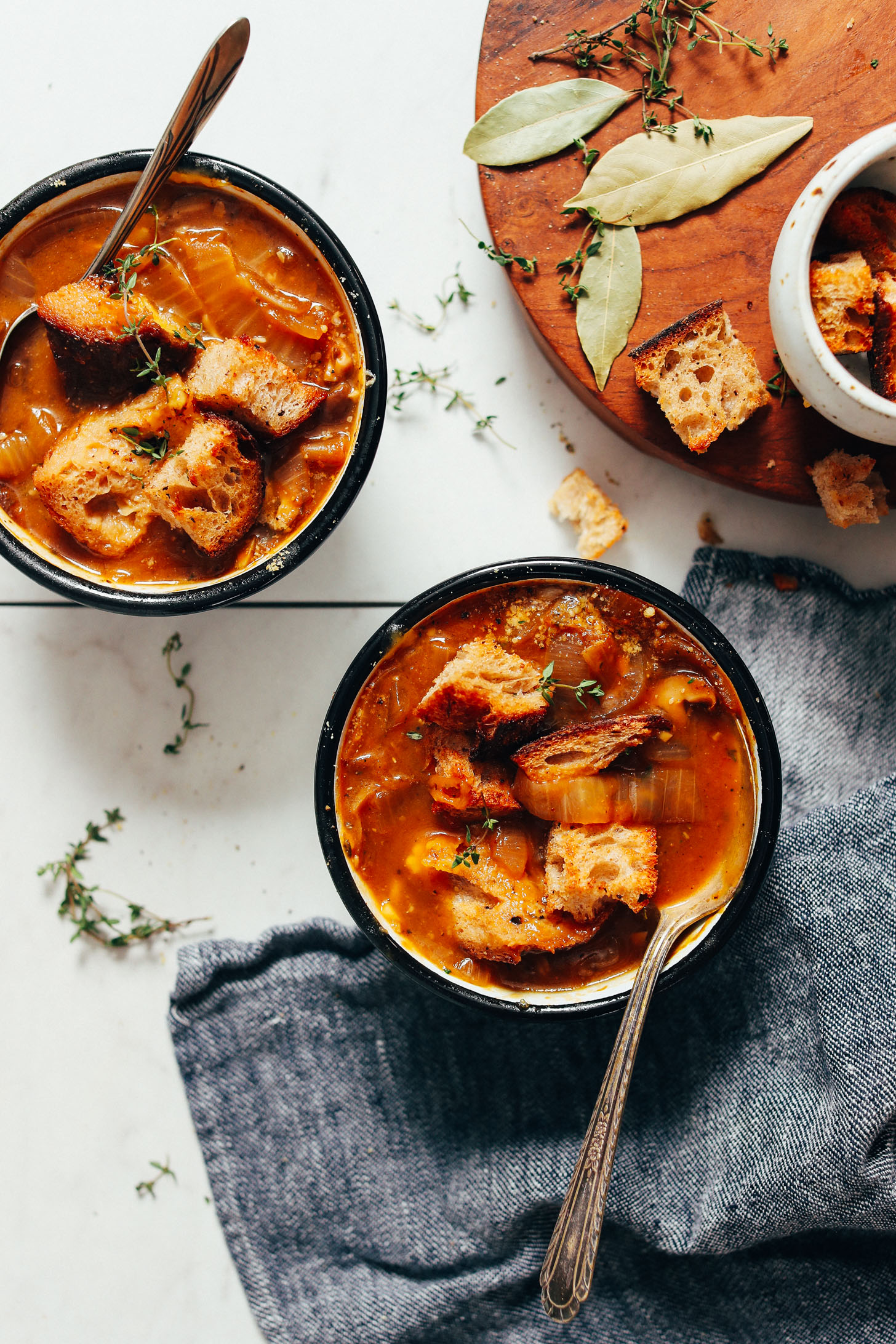 Two bowls of vegan French onion soup topped with fresh thyme