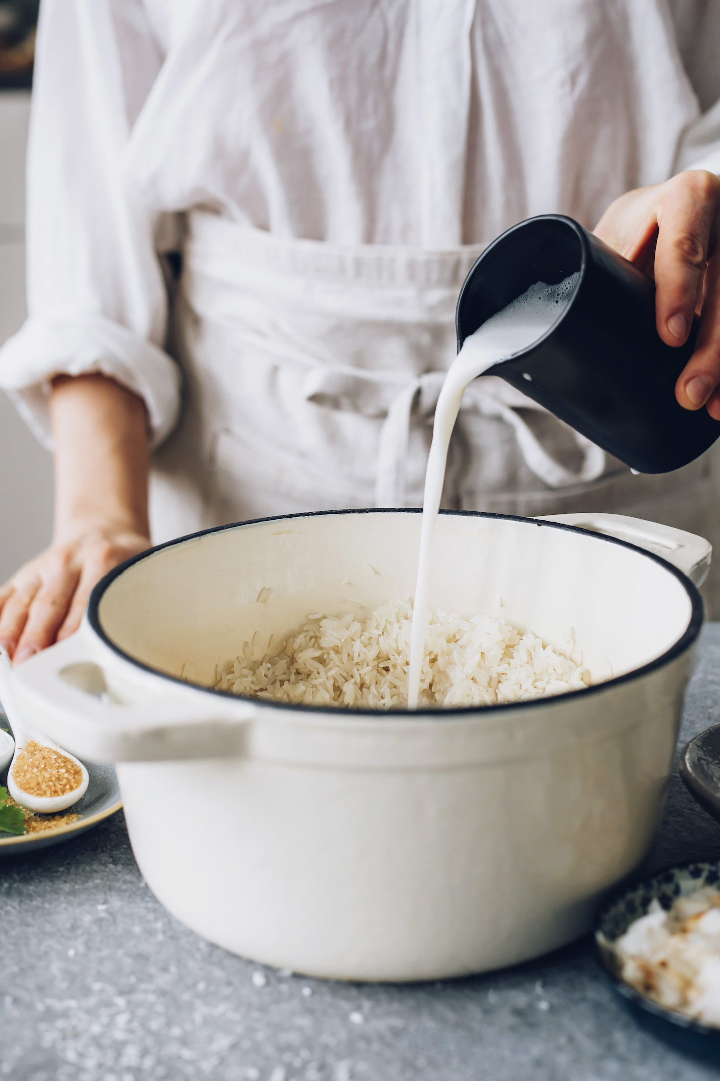 Pouring coconut milk into a pan of rice