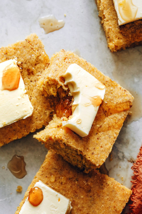 Slices of perfect vegan cornbread drizzled with vegan butter and maple syrup
