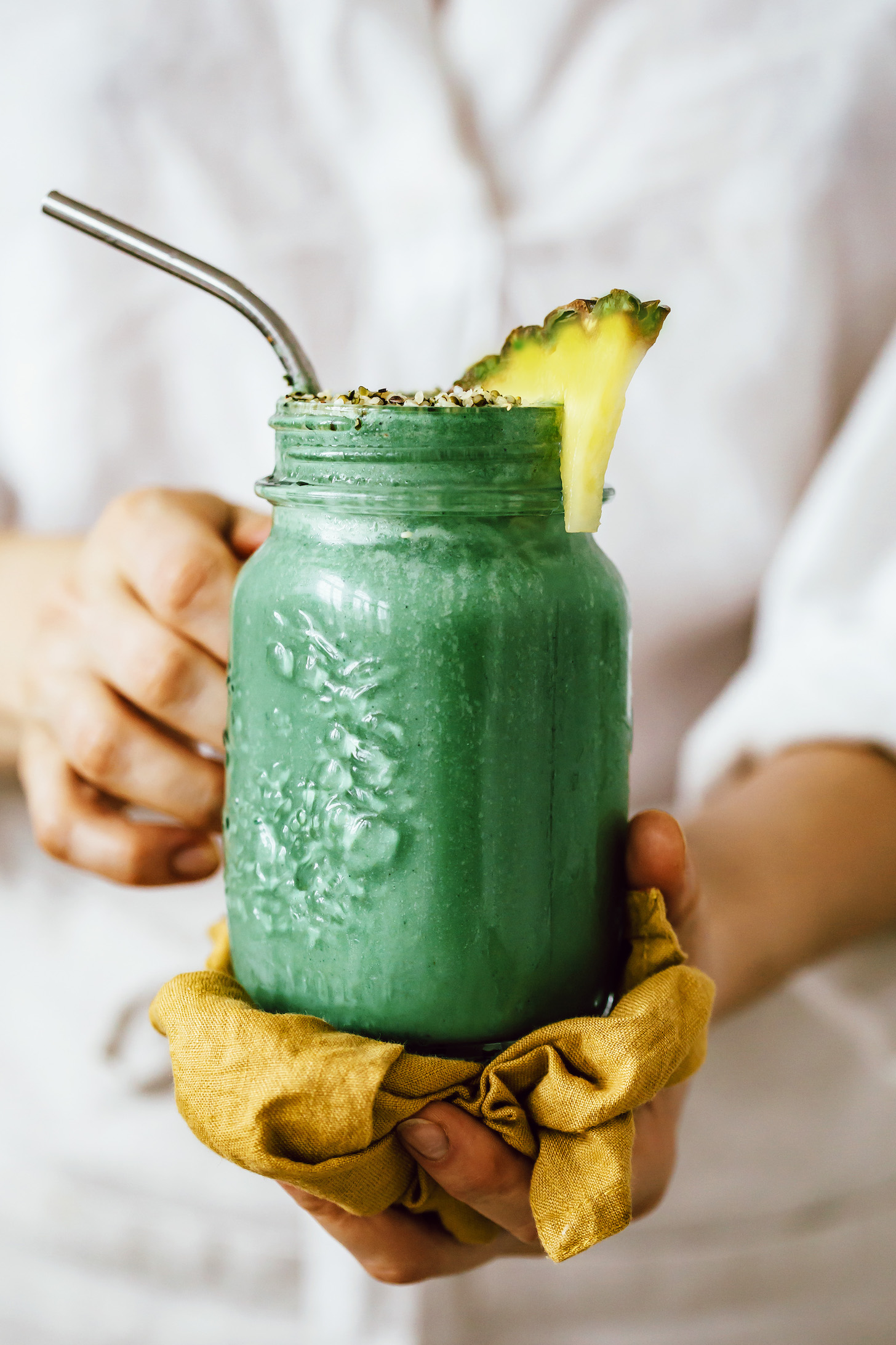 Holding a glass jar of our tropical green smoothie