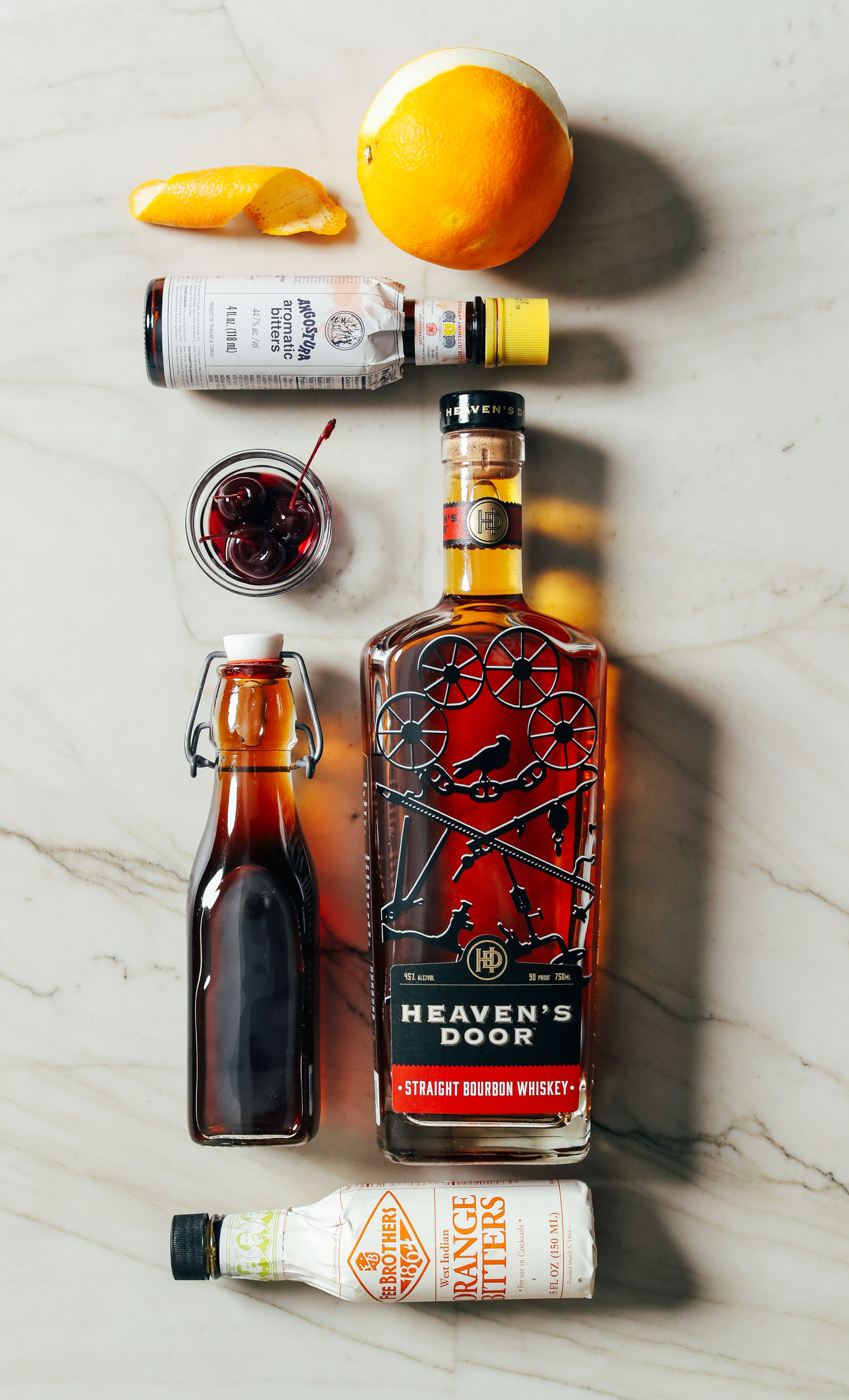 Orange, bitters, cocktail cherries, simple syrup, and bourbon whiskey for making an Old Fashioned