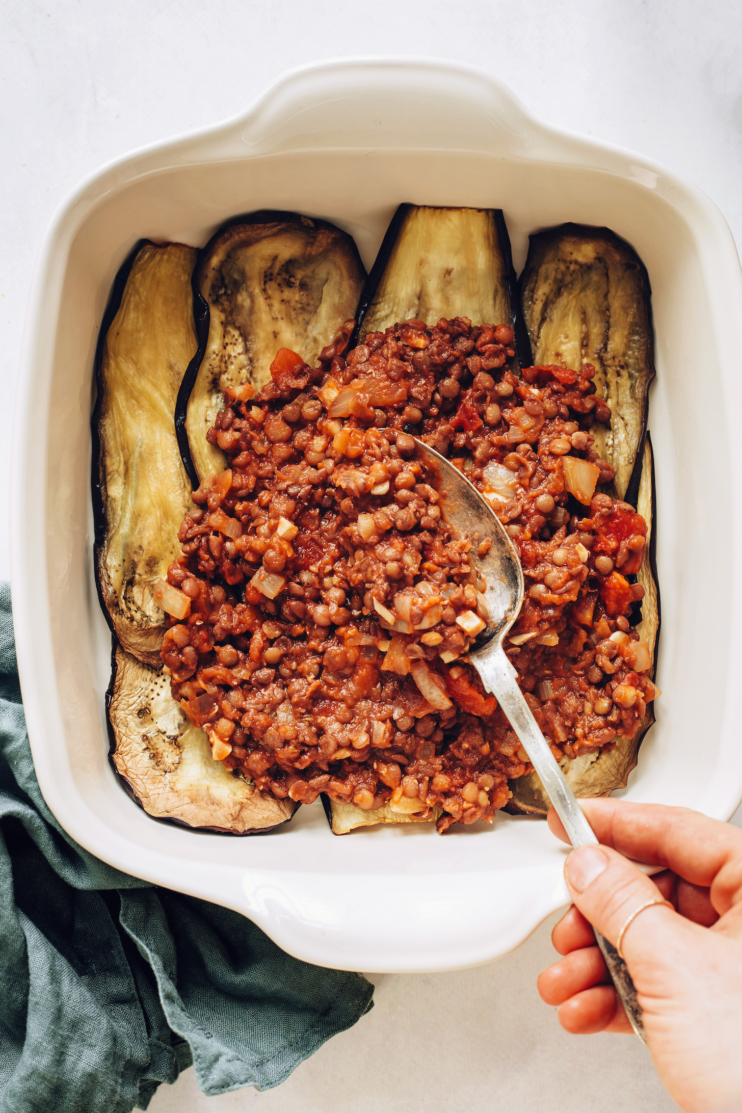 Pouring lentil filling over baked eggplant slices