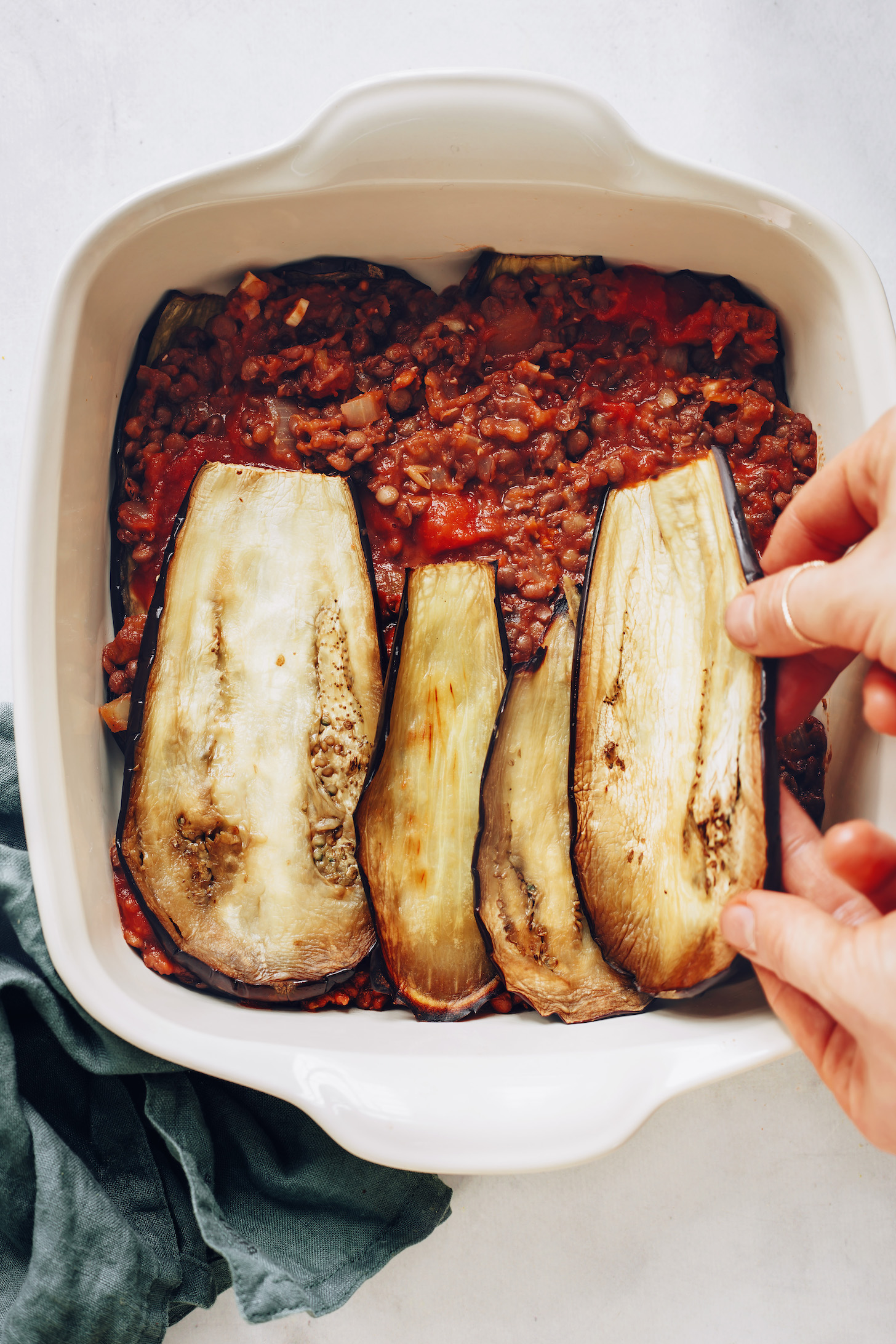Adding eggplant slices over a lentil tomato filling