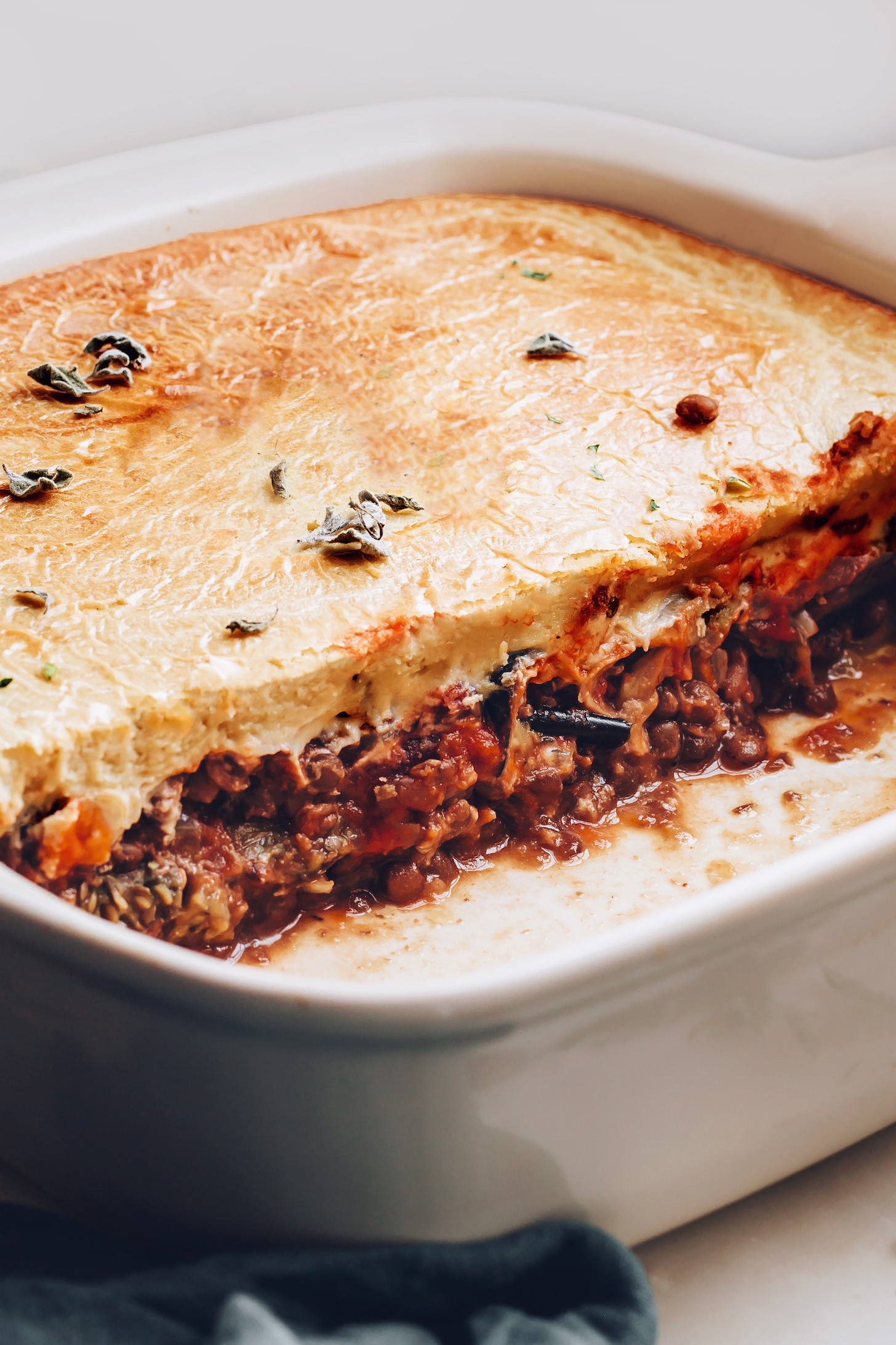 Ceramic pan of vegan moussaka topped with oregano