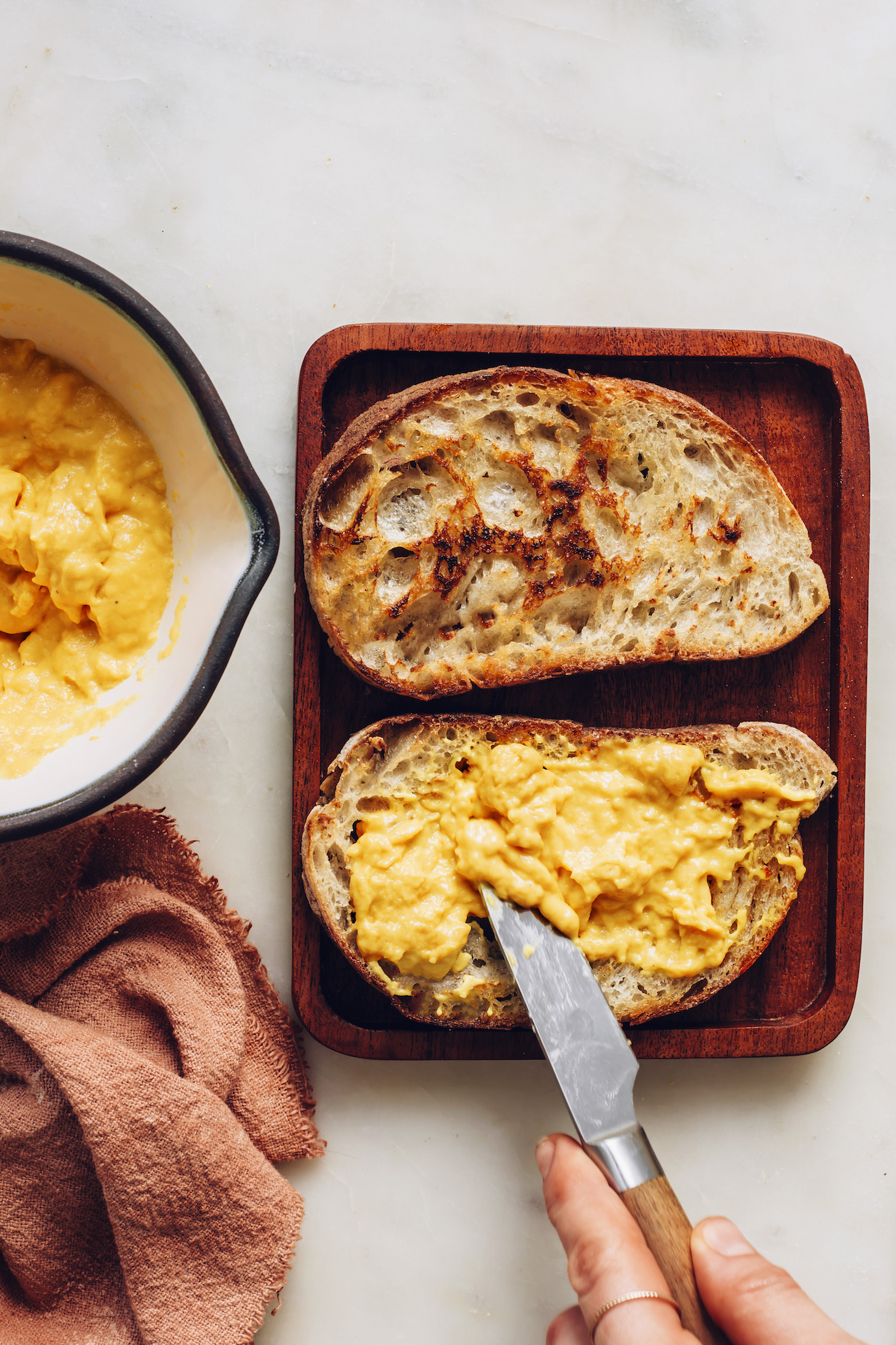 Spreading vegan cheddar cheese onto sourdough bread
