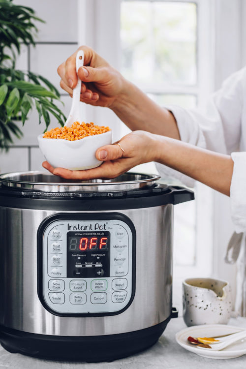 Holding a bowl of red lentils over an Instant Pot