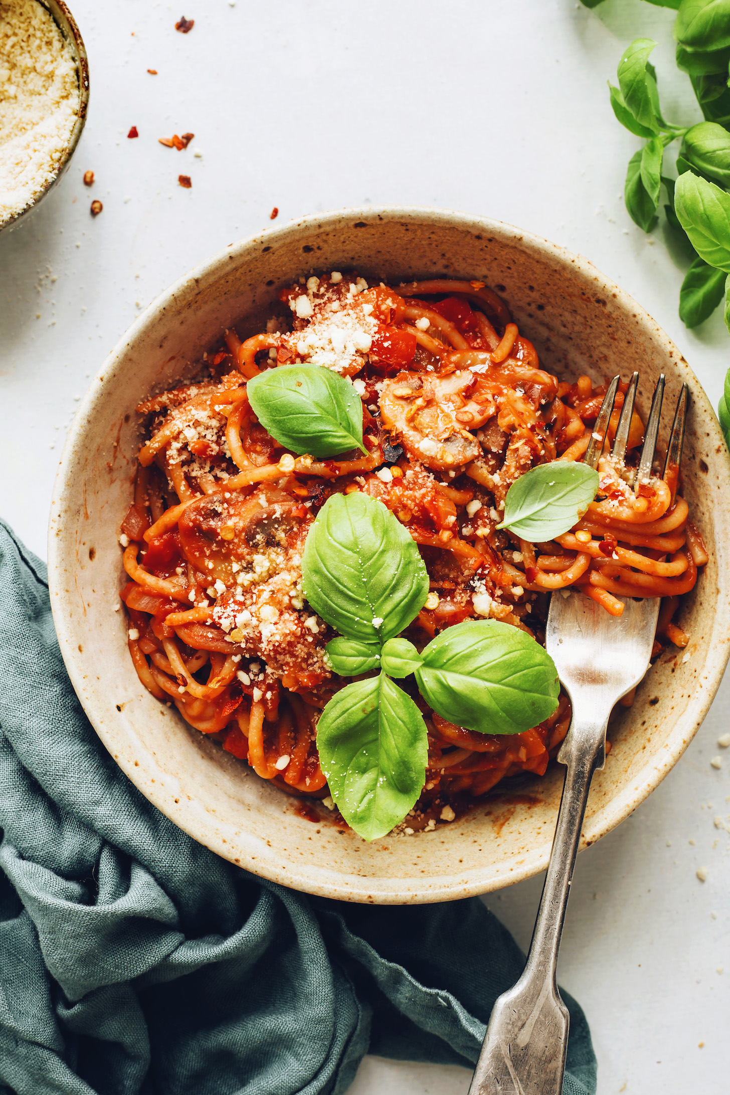 Fork in a bowl of vegan spaghetti topped with fresh basil