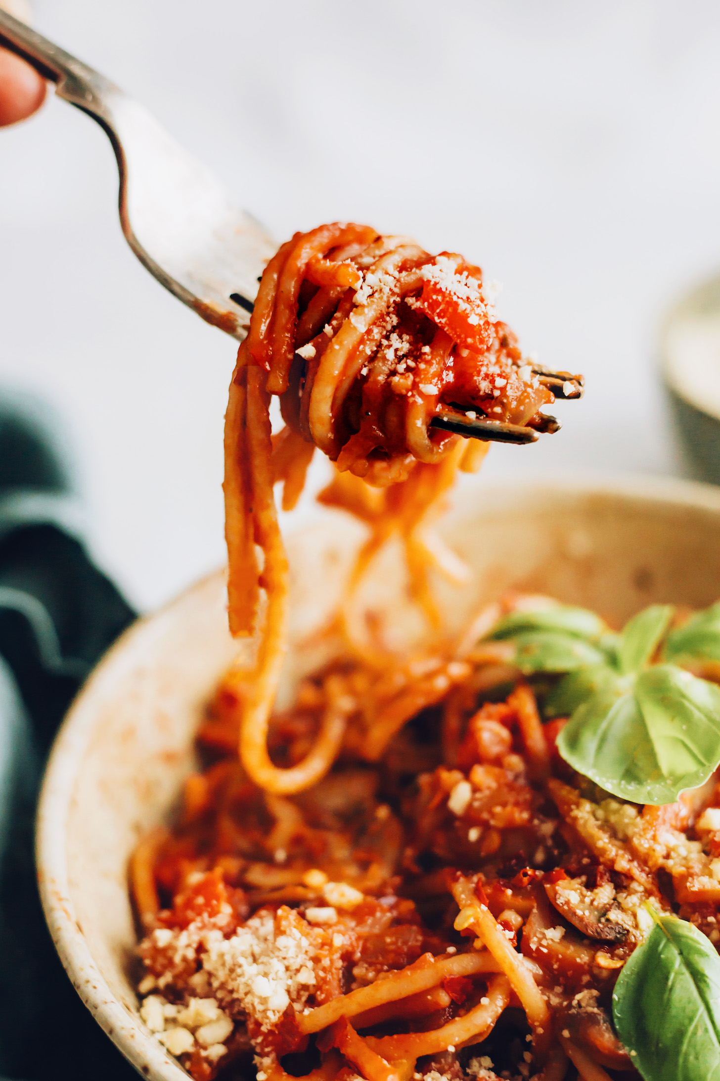 Close up shot of a bite of 1-pot vegan spaghetti topped with vegan parmesan cheese