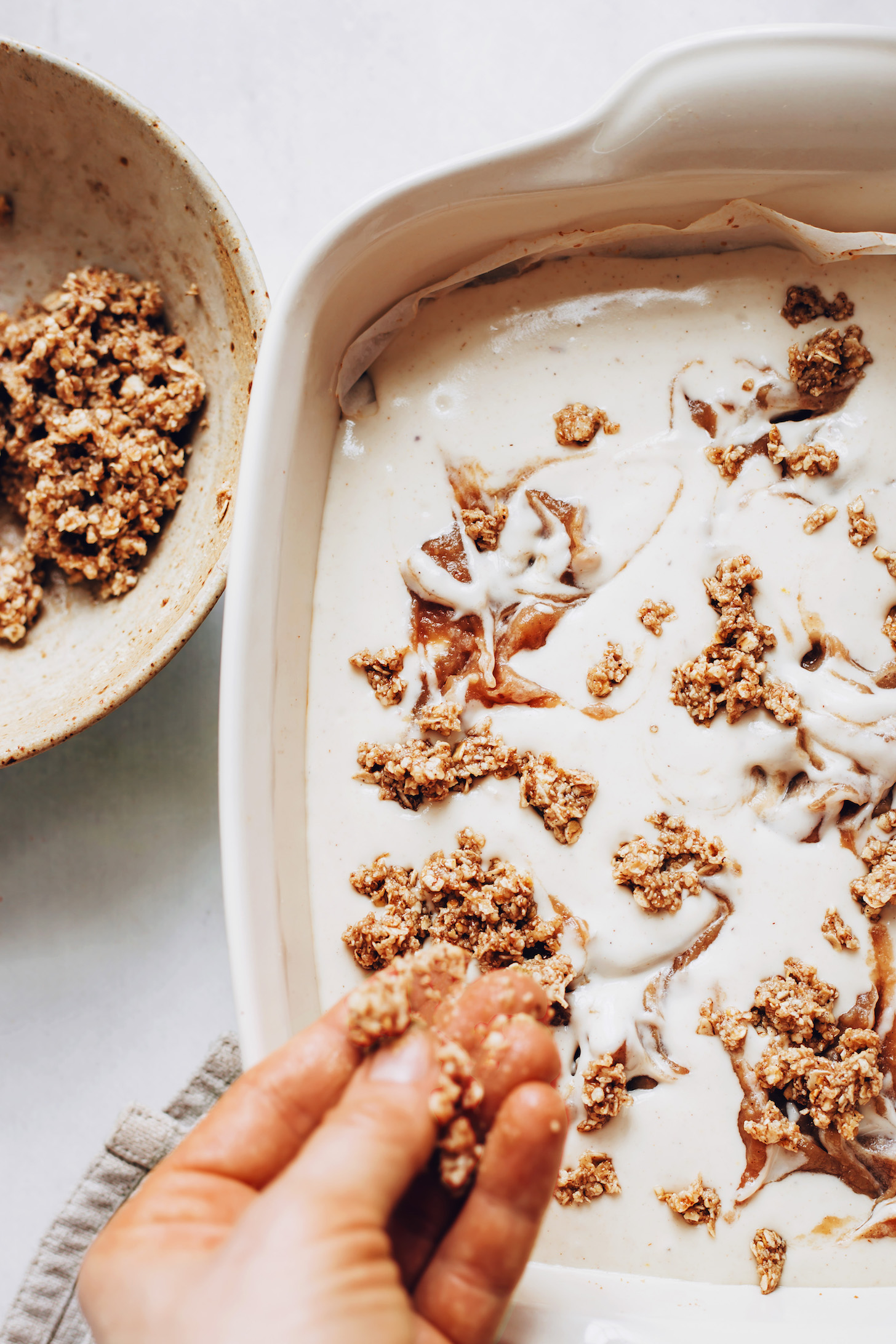 Sprinkling a crumble topping over cheesecake