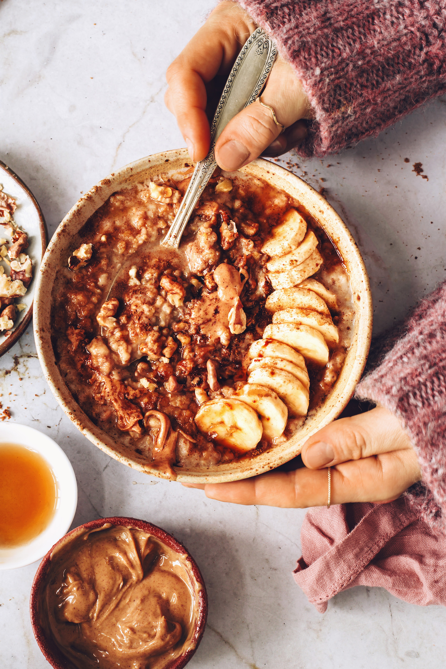 Nut butter, walnuts, and maple syrup next to a bowl of banana bread oats