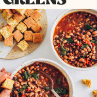 Holding a piece of cornbread in one hand and picking up a spoonful of black eyed peas and greens in the other