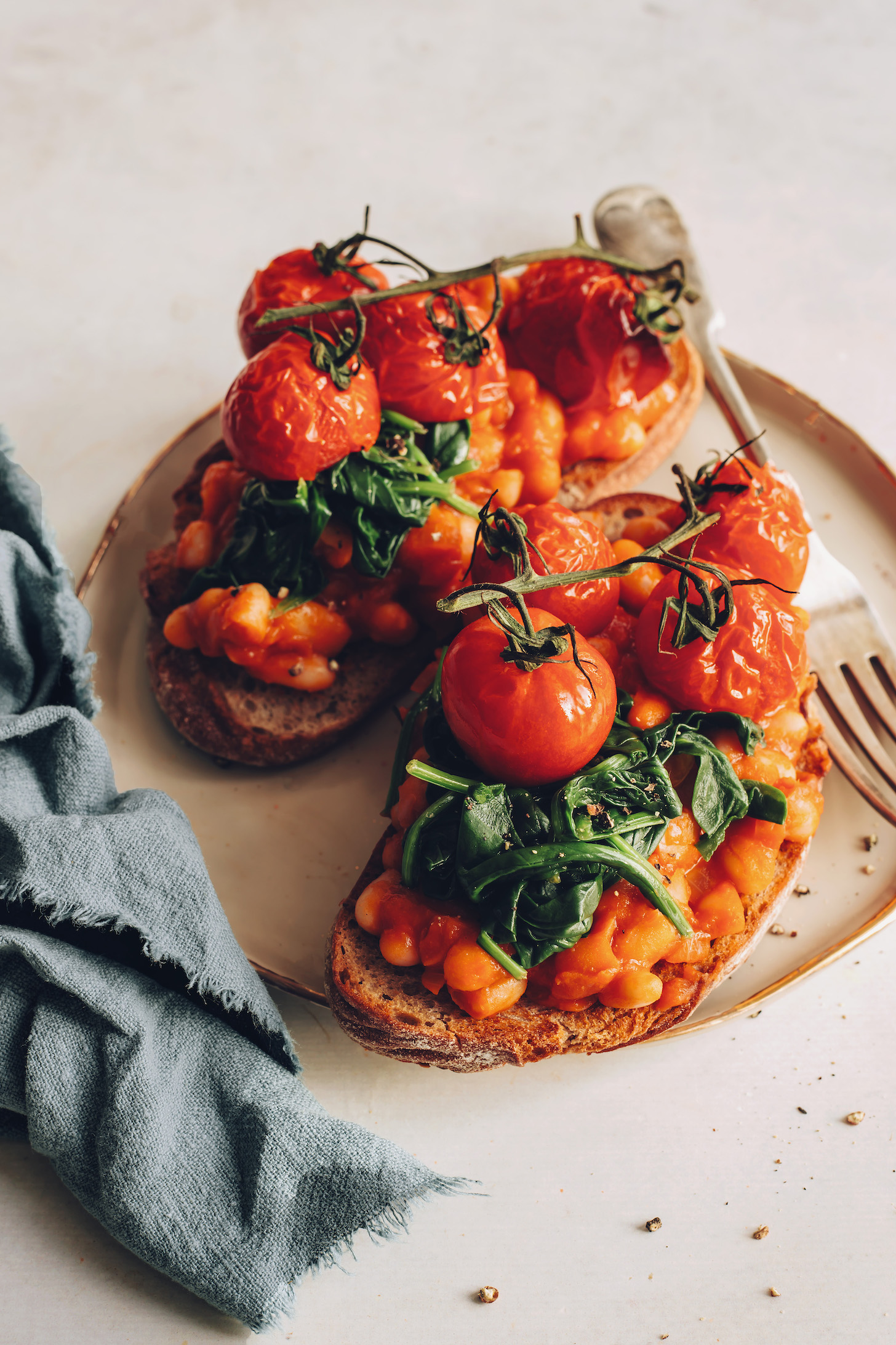 Slices of sourdough bread topped with British baked beans, wilted spinach, and slow roasted tomatoes