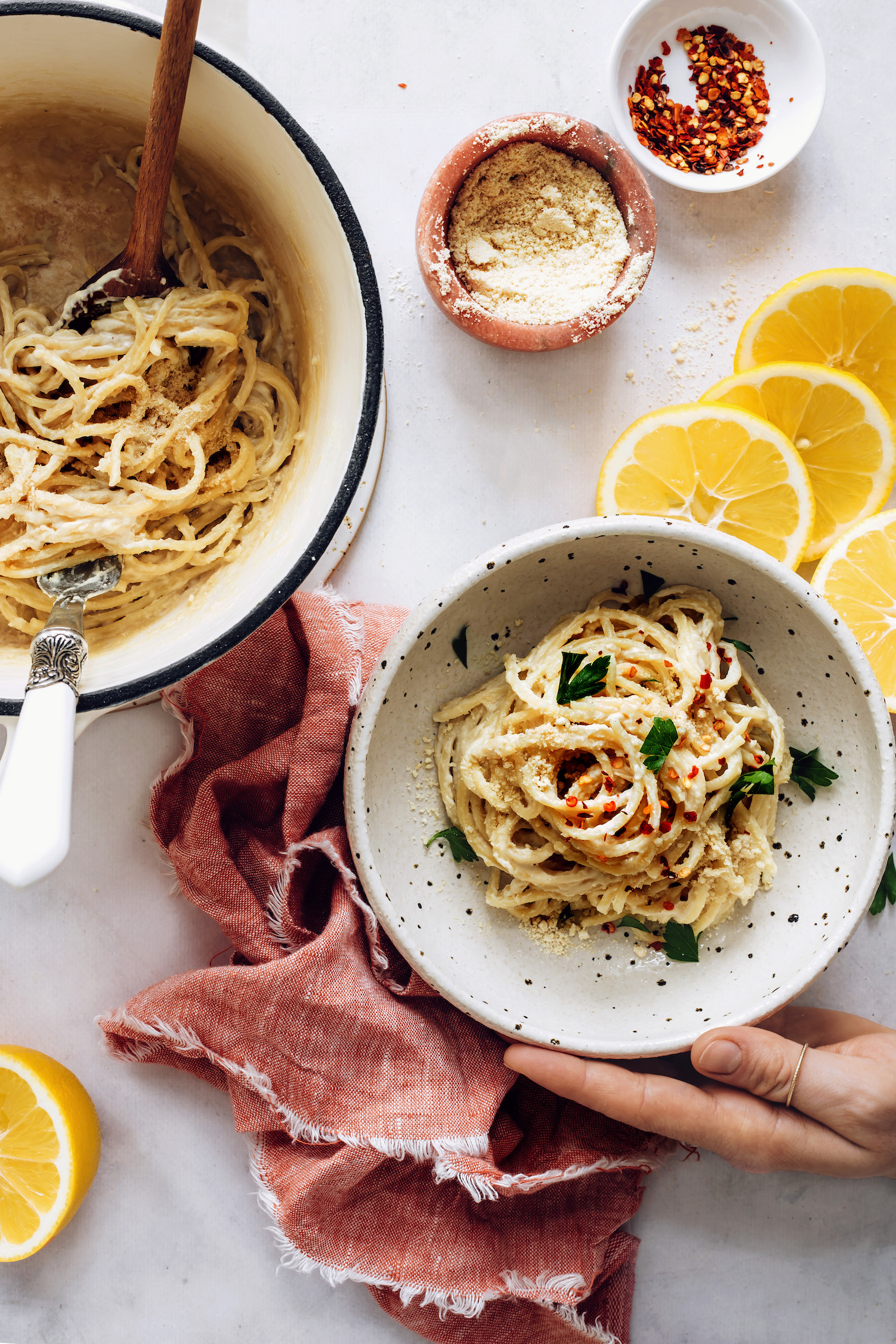 Bowl and pan of vegan lemon pasta topped with red pepper flakes and parsley