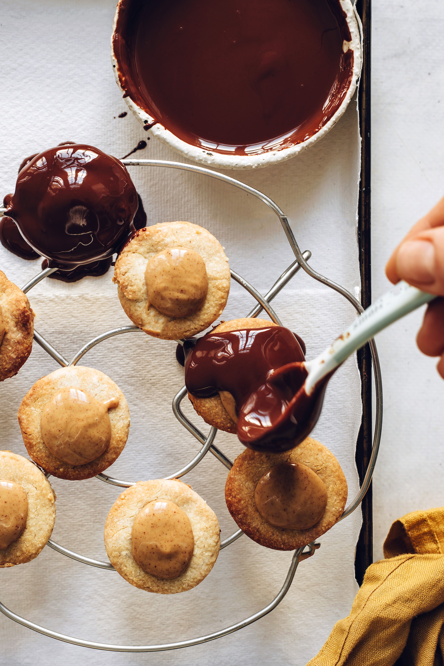Using a spoon to top peanut butter patties with melted chocolate
