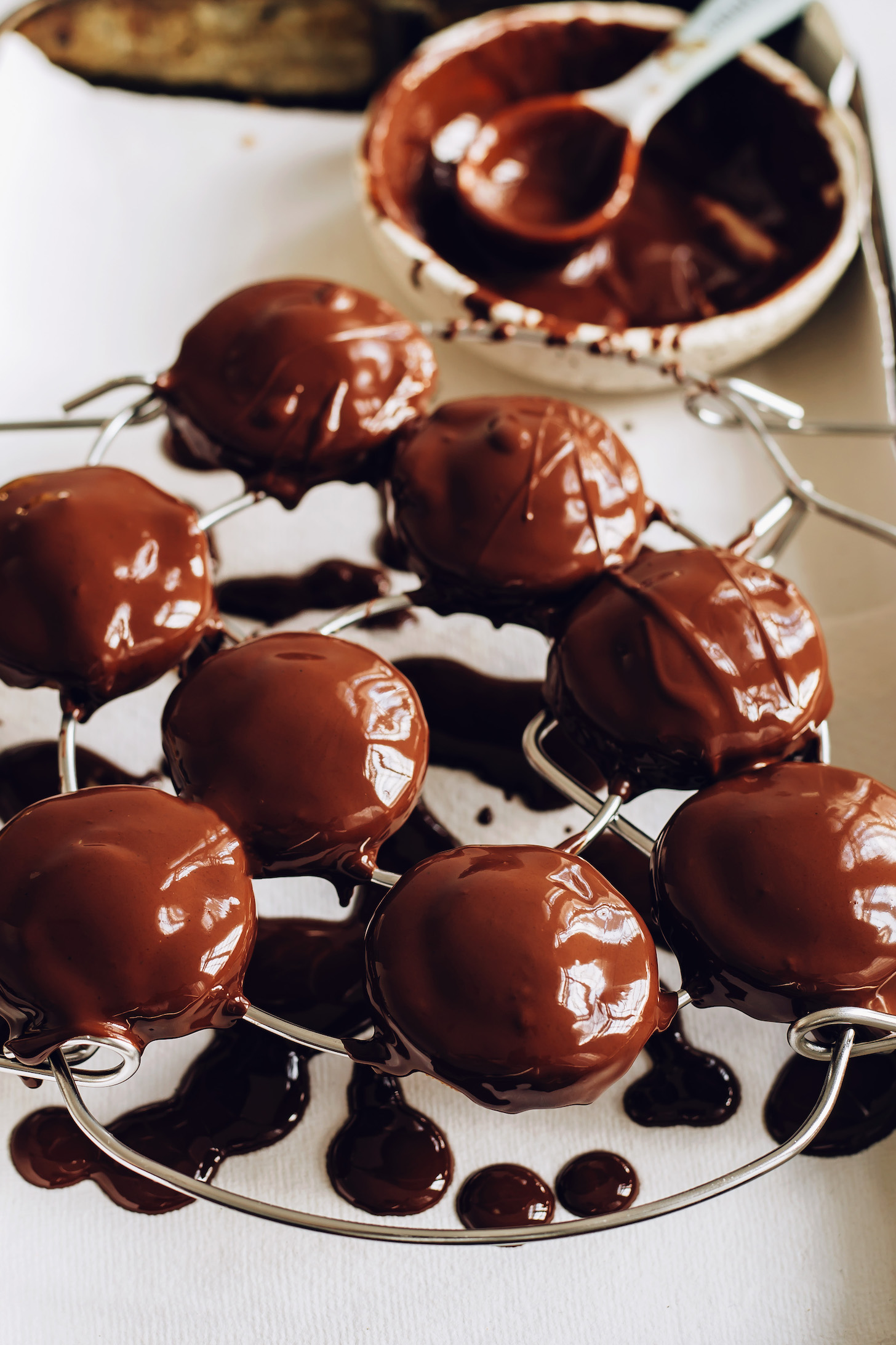 Bowl of melted chocolate next to a rack with chocolate peanut butter patties